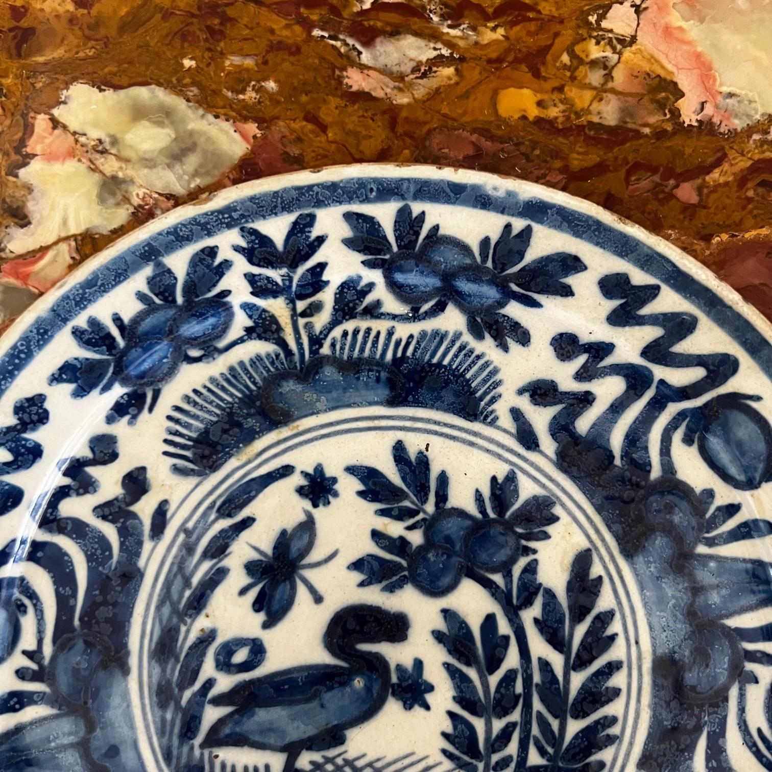 Assiette de cabinet en faïence hollandaise du 18e siècle. Poterie artisanale en terre cuite émaillée à la main, entièrement peinte à la main dans un décor floral bleu et blanc. Au centre, un oiseau avec des fleurs entourées d'arbres. Origine :