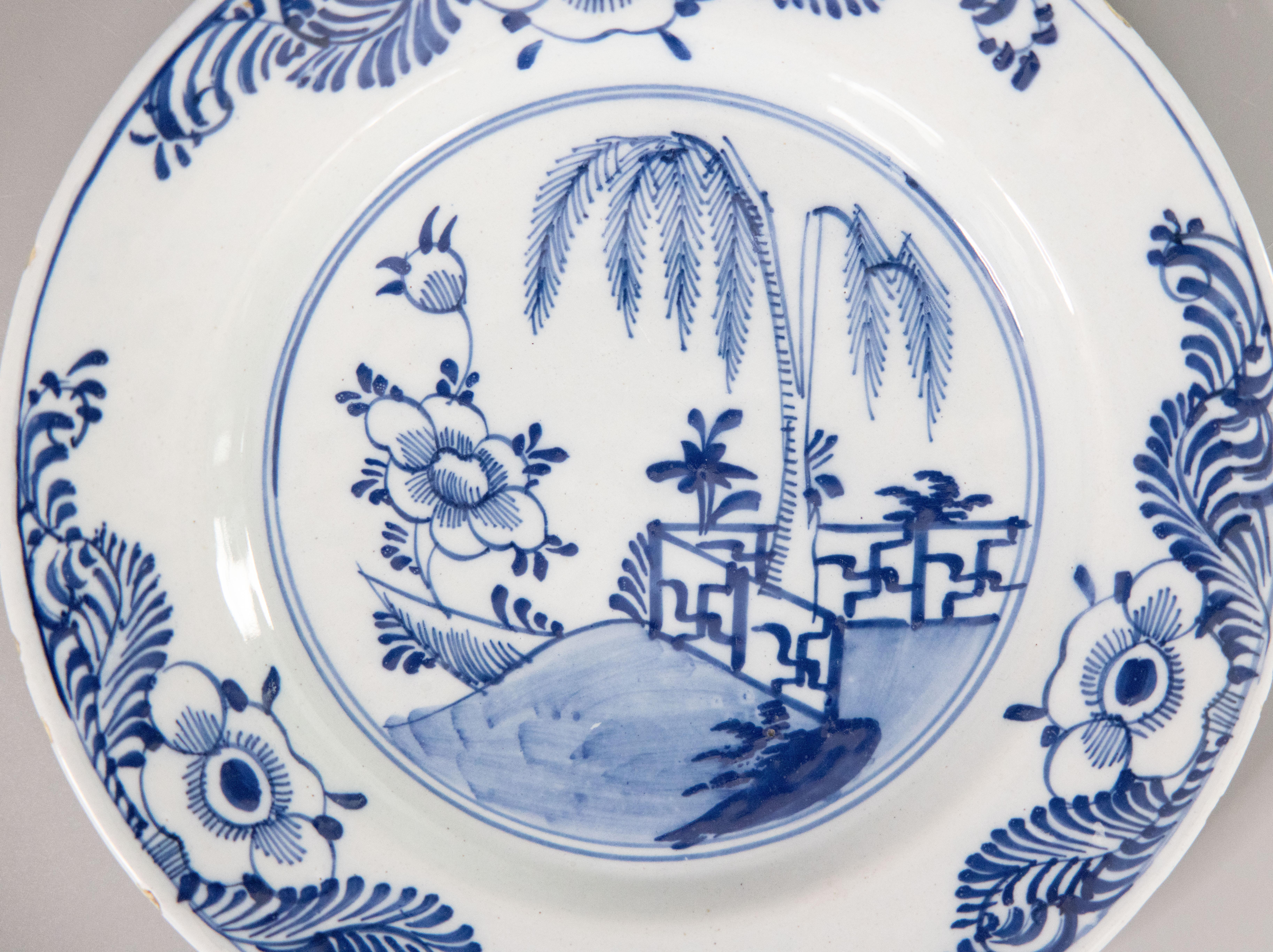 Superbe assiette à jardin fleuri en faïence de Delft Chinoiserie hollandaise du 18e siècle. Cette jolie assiette est ornée de fleurs, d'une clôture, d'un arbre et d'une bordure feuillue peints à la main en bleu cobalt et blanc. Elle serait