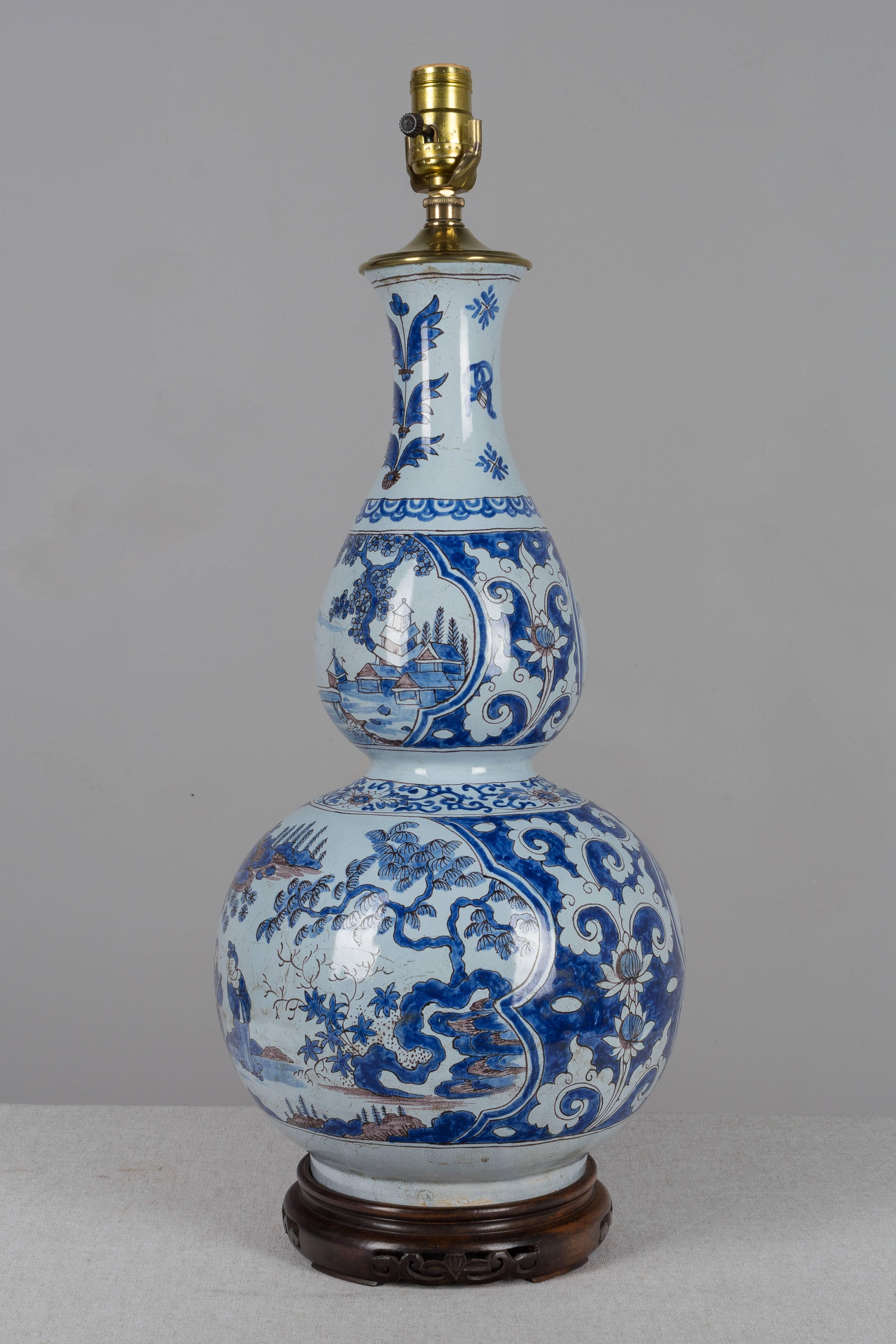 An 18th century delft faience double gourd form vase converted to a lamp. Hand-painted chinoiserie motif in indigo blue on pale blue ground. Vase is 19