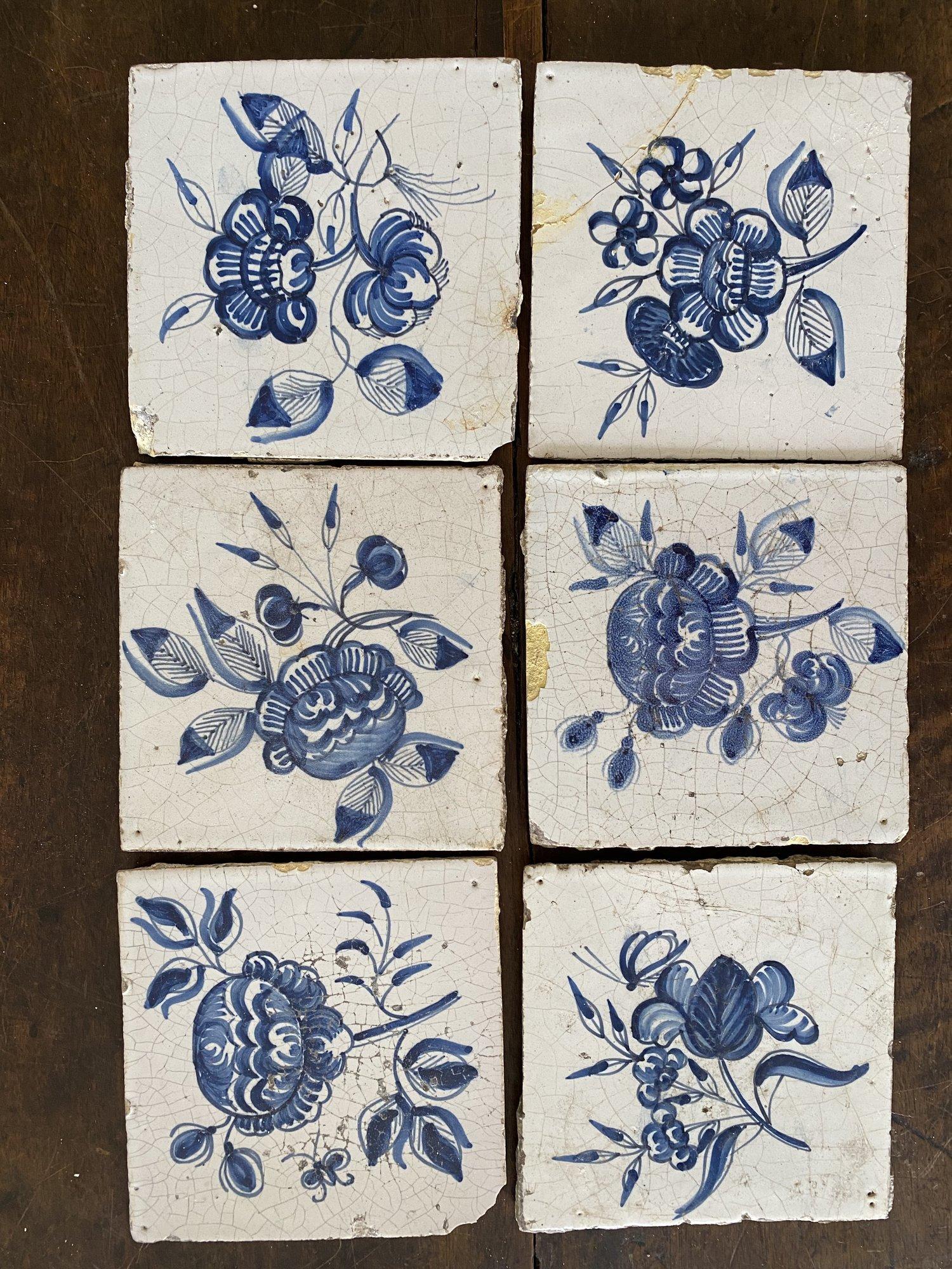 Set of seven 18th century Delft blue and white floral tiles, in various condition.