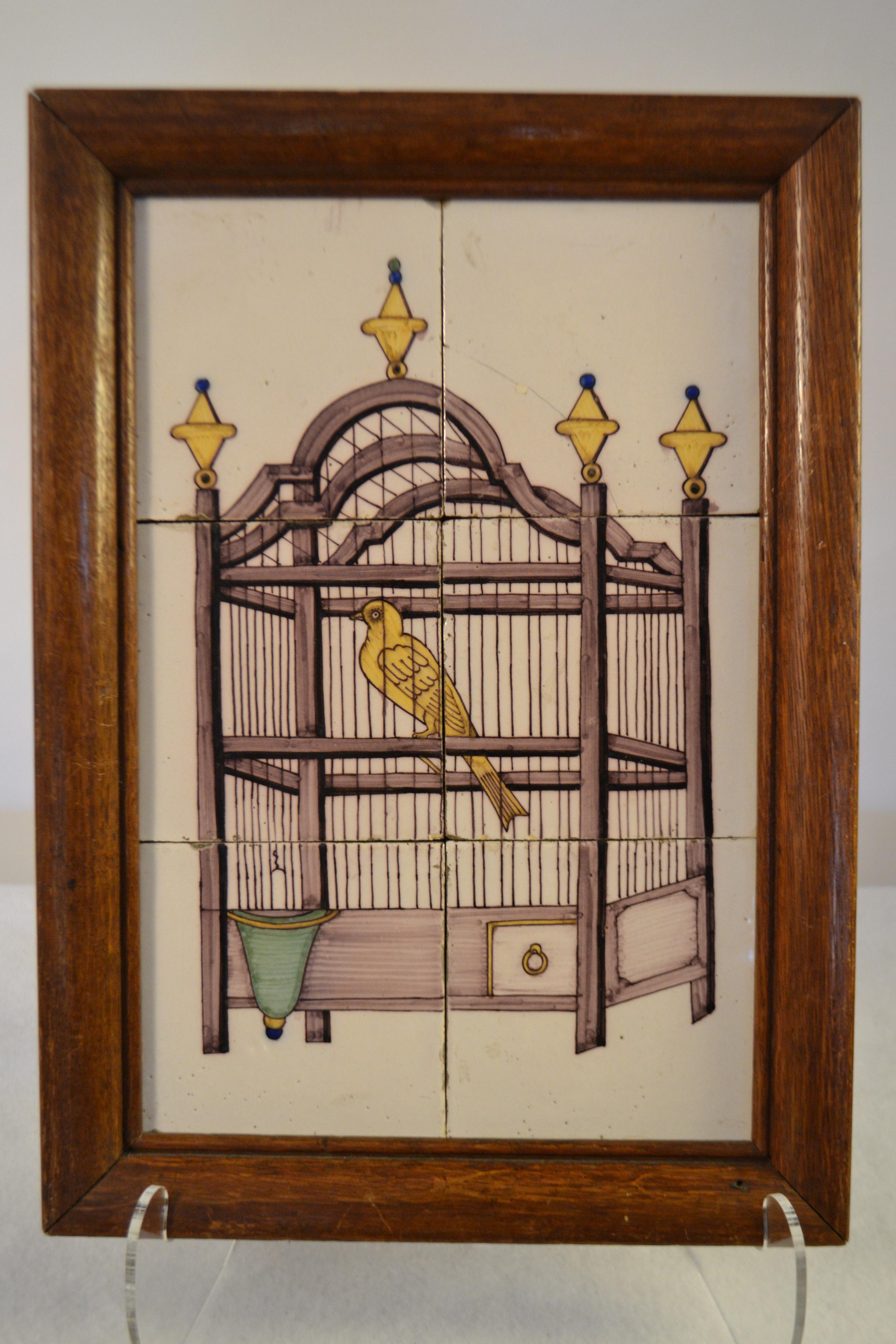 18th century delft tile wall picture of a bird in a cage with a manganese based purple colored cage, a yellow bird, yellow and blue finials, and a green water bowl.