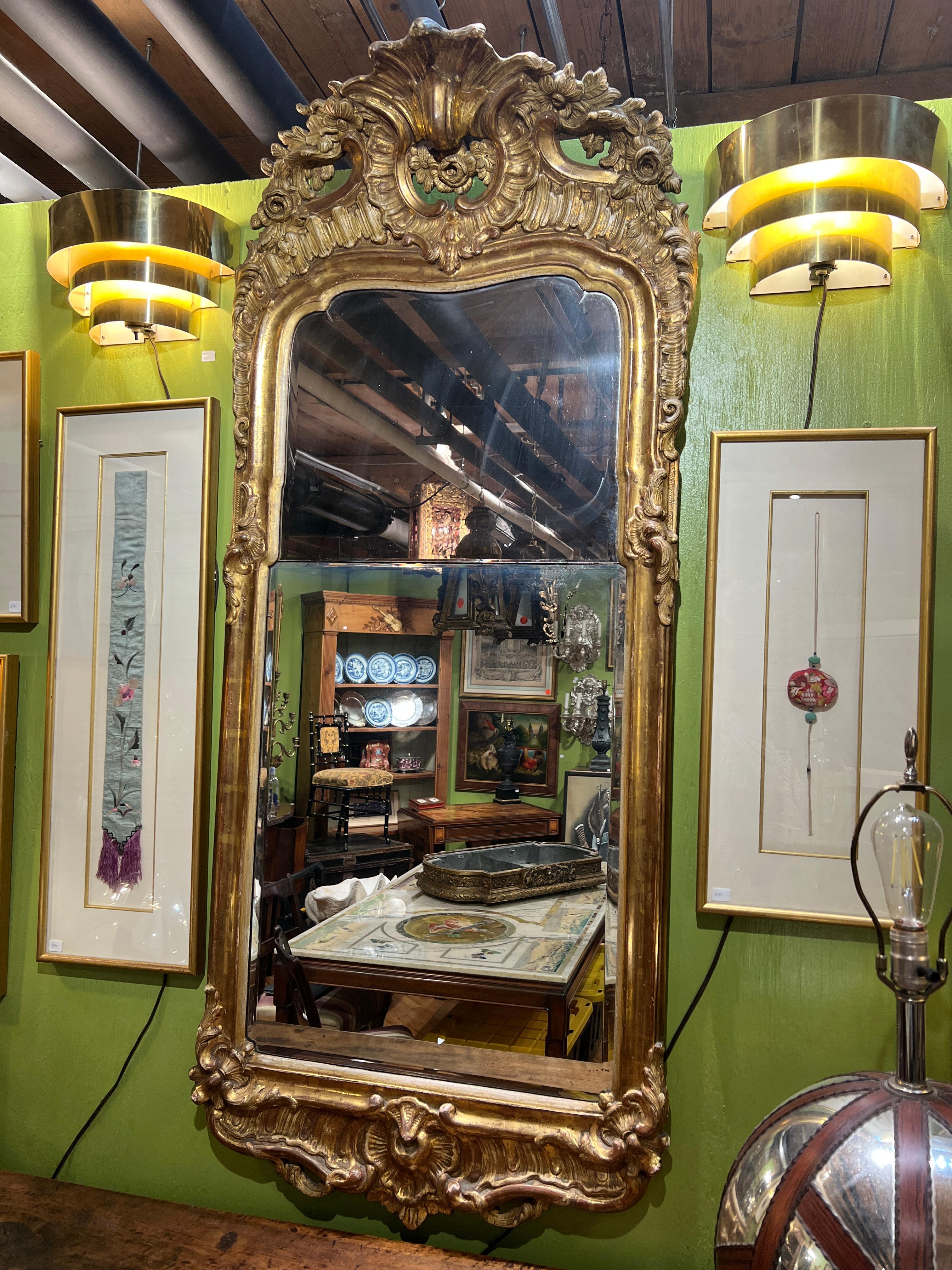English, 18th century.

This exceptional 18th-century Queen Anne mirror is a testament to the refined elegance and sophistication of the period. Crafted from giltwood and featuring original double-paned beveled glass, the mirror showcases the