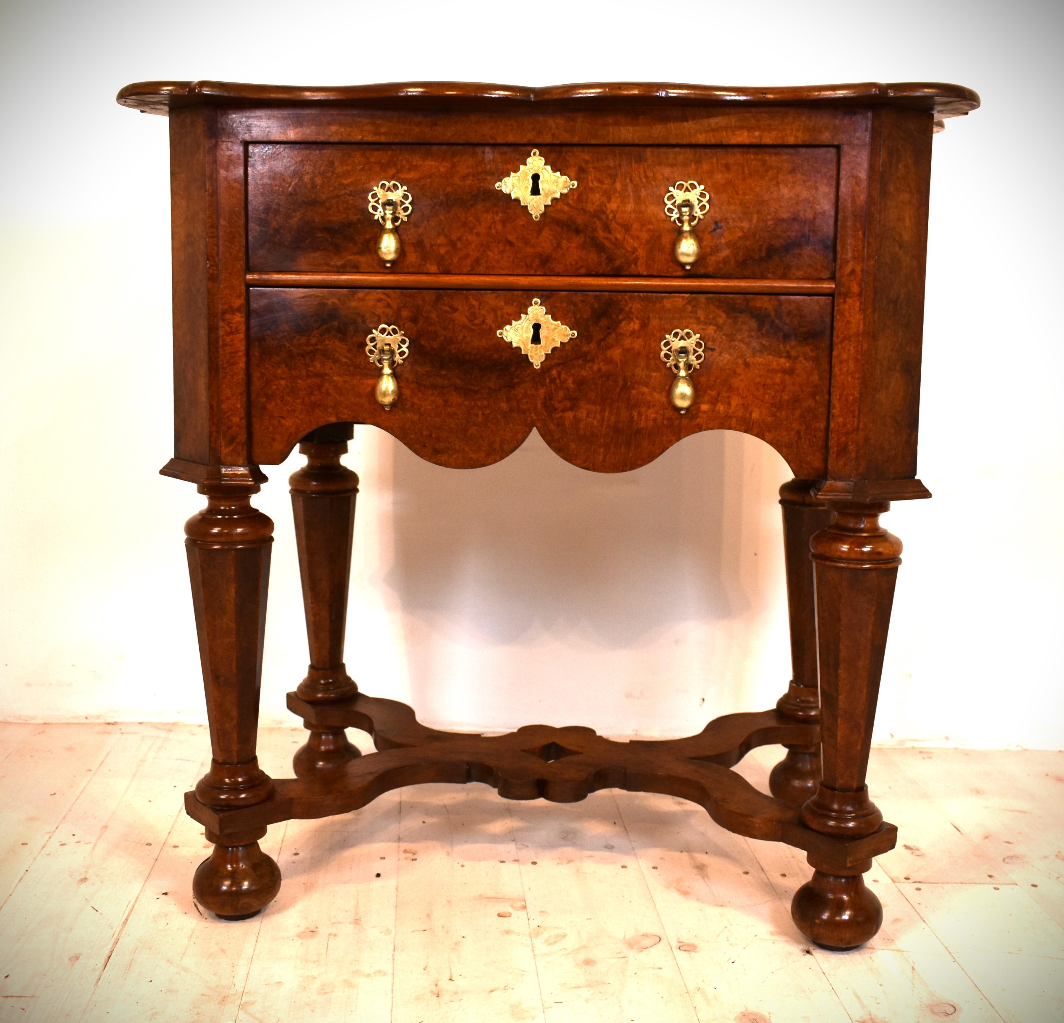 Here we have a Dutch side table or lowboy with two drawers with wavy stretchers on bun feet.It also has a lovely shaped top. The special thing about the piece is the fact that the whole table is veneered in burl Amboyna This wood is usually only
