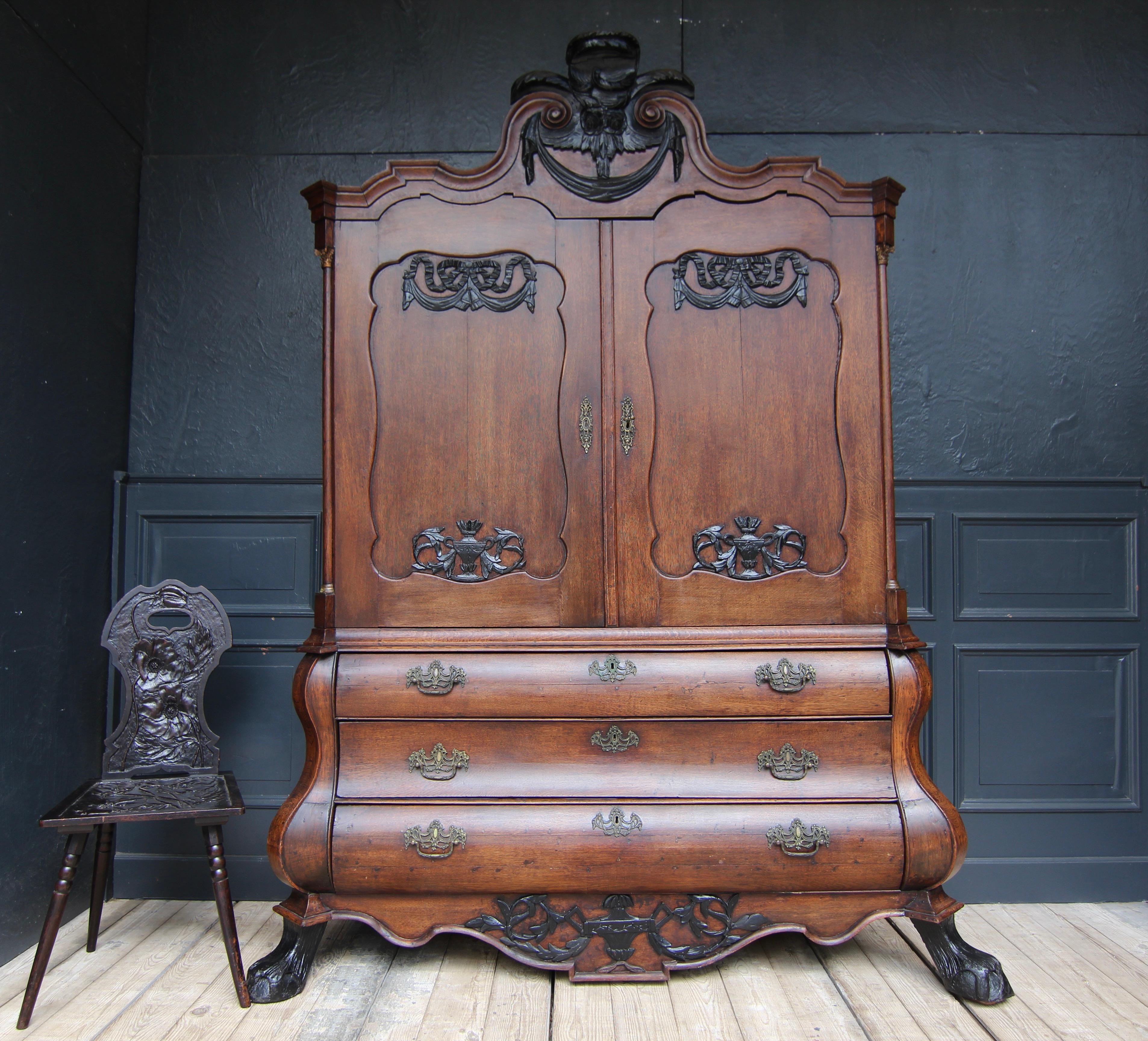 Armoire ou presse à linge baroque hollandaise de la 2e moitié du 18e siècle. Fabriqué en chêne, il est rehaussé d'une décoration sculptée ébonisée et de ferrures en bronze moulé.

Le meuble se compose d'une base de coffre à trois baies avec une