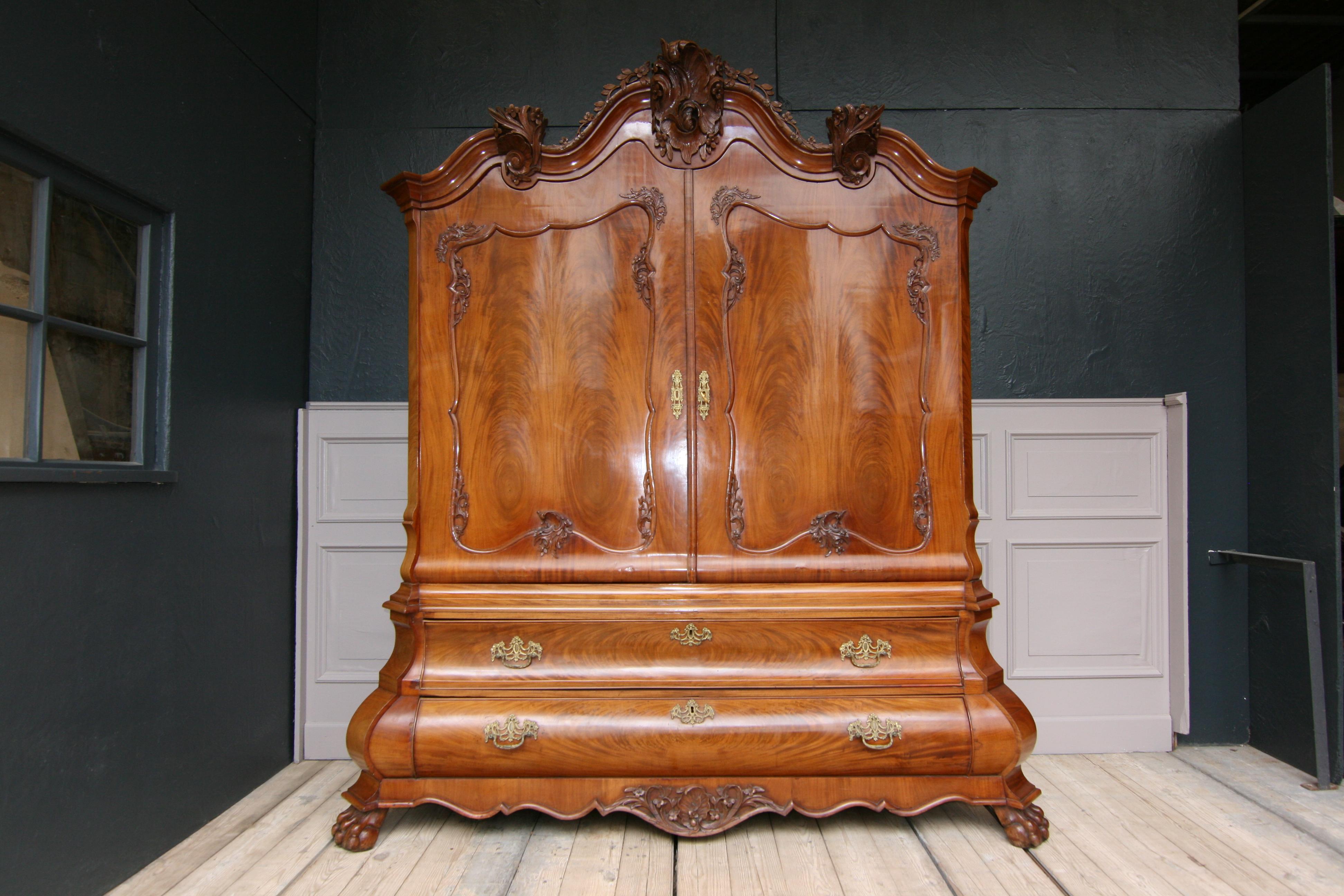 An 18th century Dutch baroque linen press or cabinet. Mahogany veneer on oak.
Bombay shaped chest of drawers standing on lion's paw feet with a strongly protruding lower and a retracted upper drawer. Laterally beveled corners that repeat the