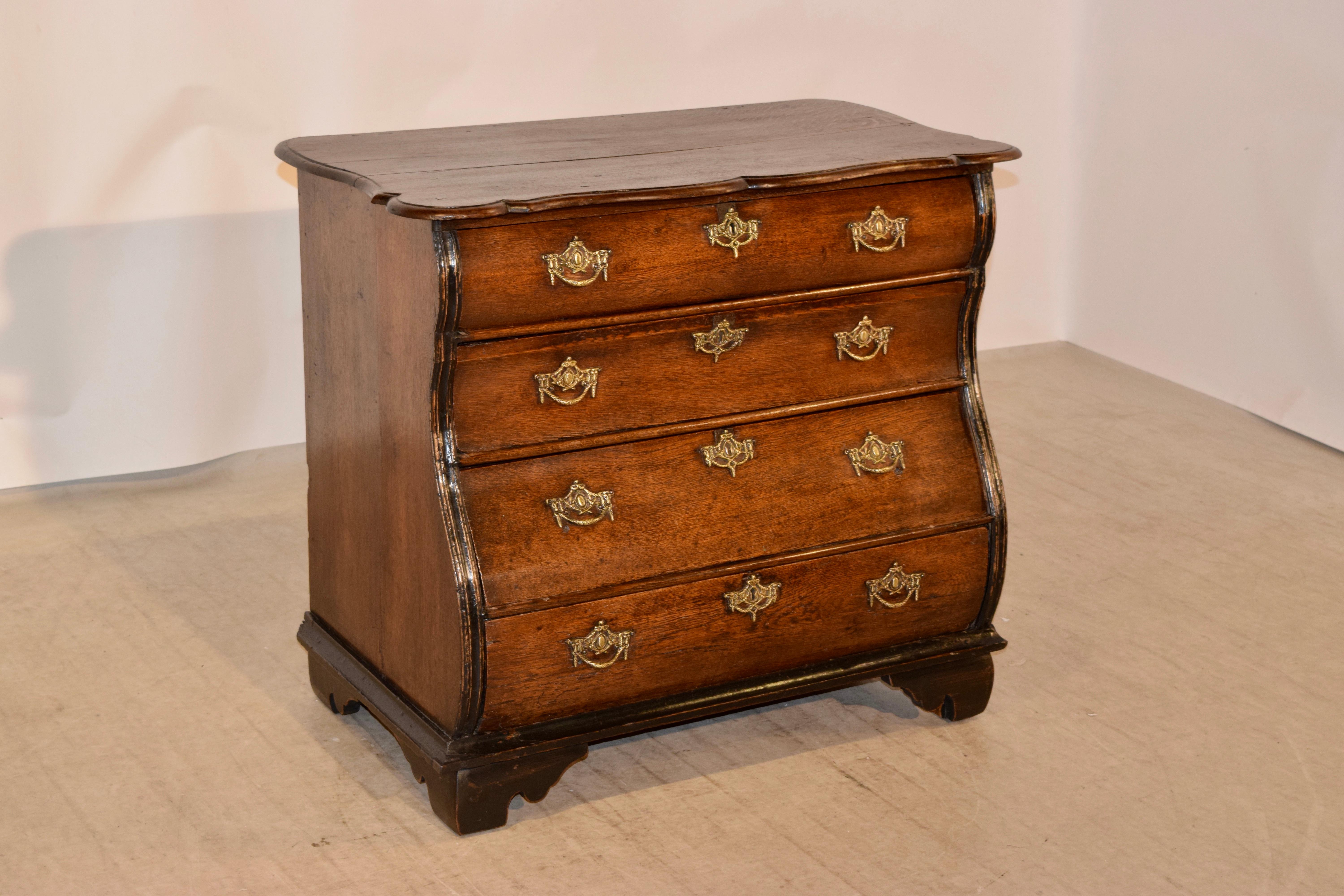 18th century Dutch bombe chest of drawers made from oak. The top has a scalloped edge, which is also beveled, following down to a serpentine shaped case with four drawers, also shaped on the drawer fronts and flanked by reeded accents and simple