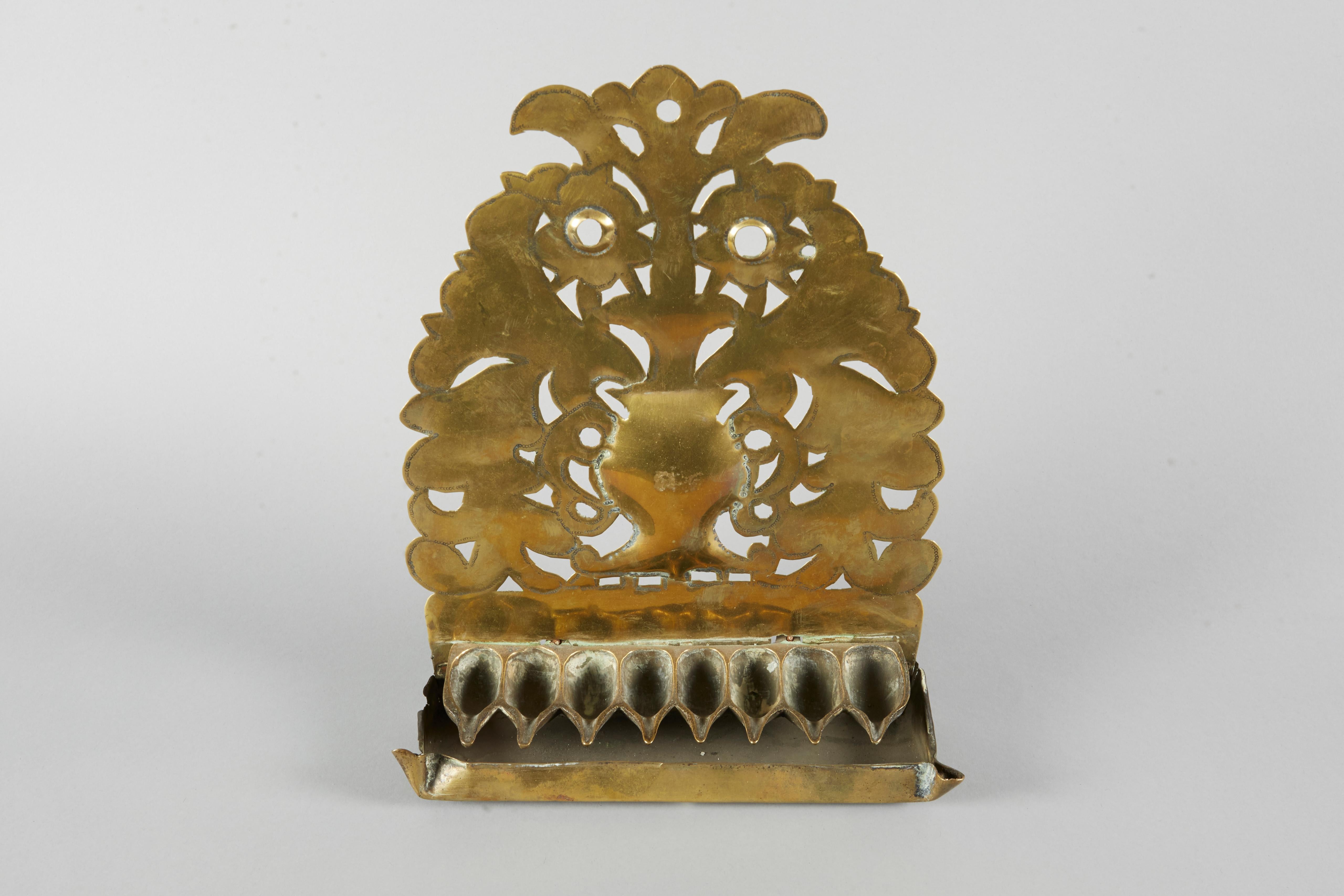 Brass Hanukkah Lamp Menorah, The Netherlands, circa 1730. 
The backplate is pierced and embossed with floral motifs around the vessel in the center and fitted with a row of eight oil pans.