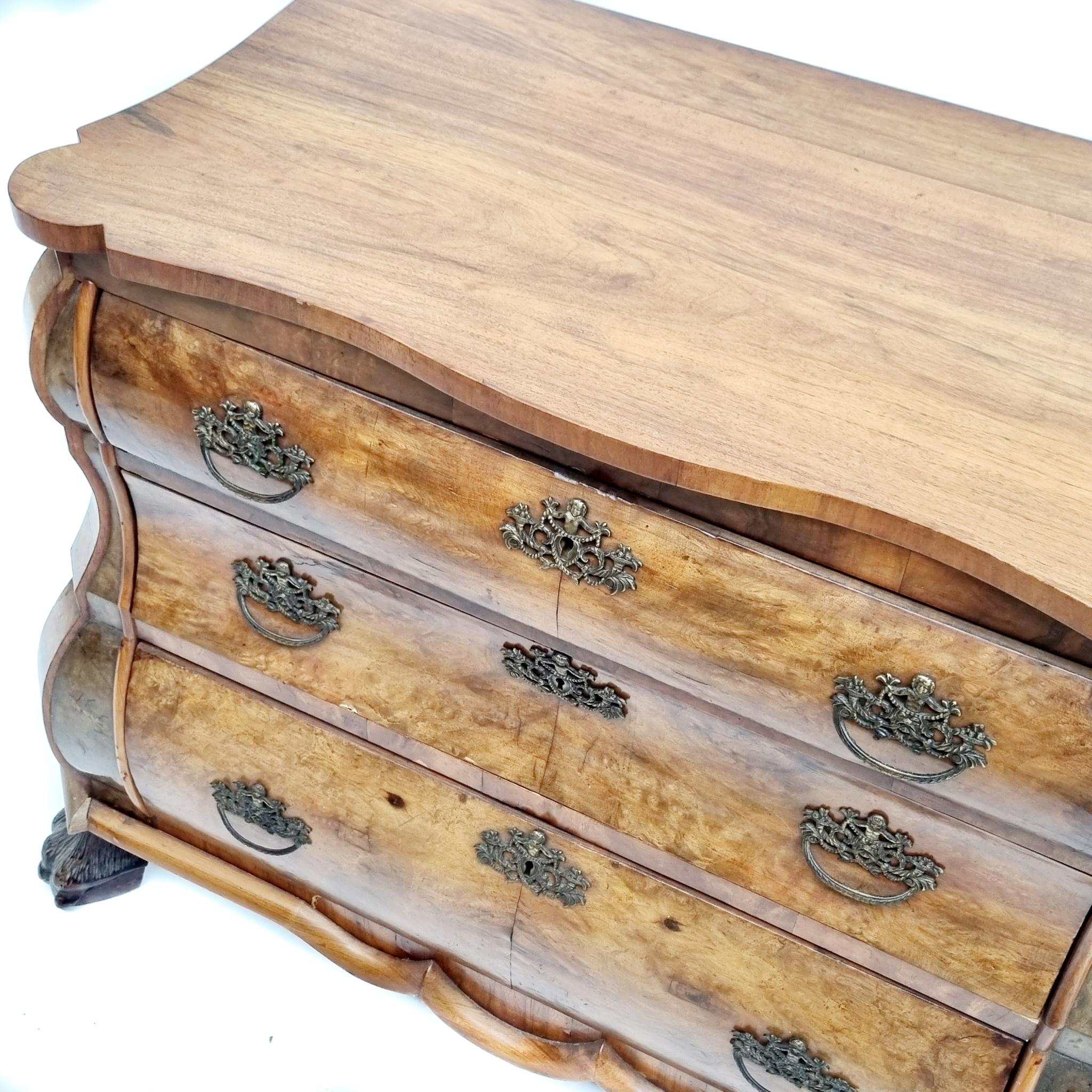 Dutch chest of 3 drawers with claw feet from the 19th century in walnut burl veneer. Good example of a 19th century Dutch design bombe shaped commode. Fitted with 3 drawers and ornate handles. Standing on 4 lion paw carved feet. Overall good vintage