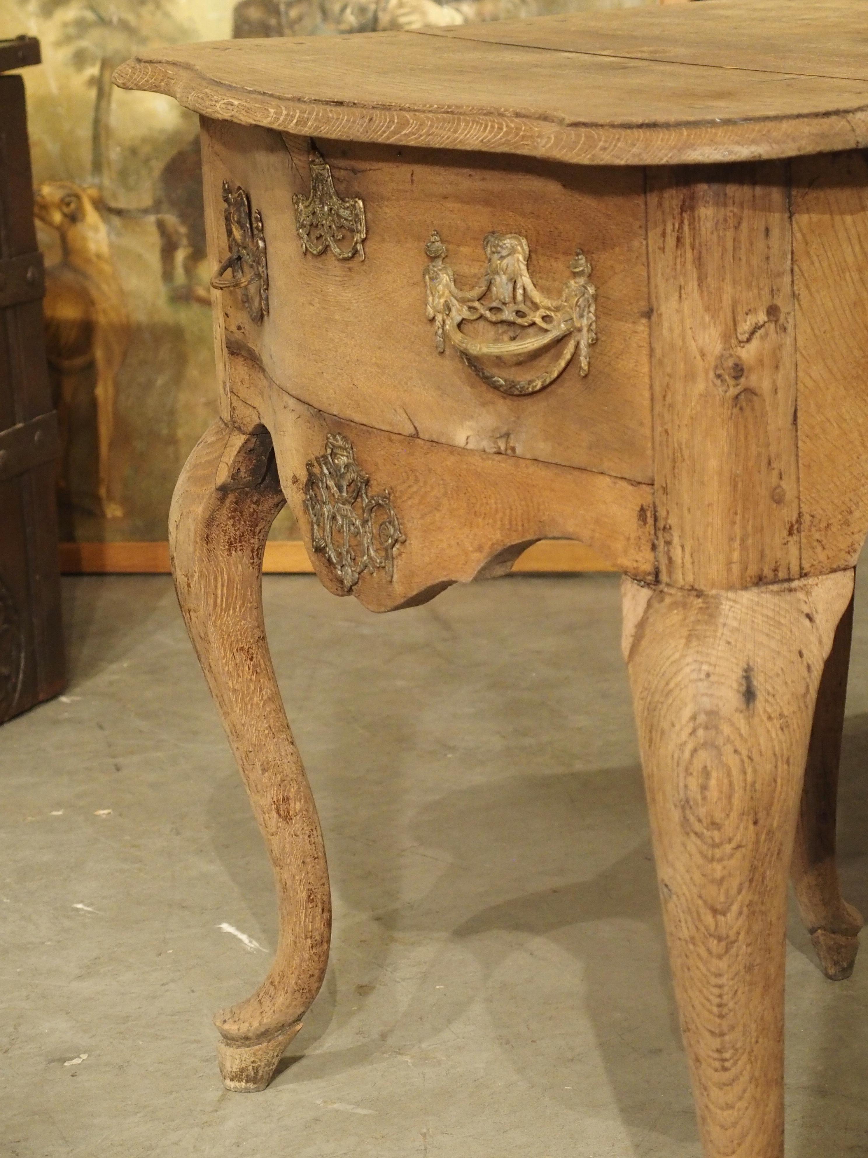 This charming oak console table was hand carved in the Netherlands during the 1700’s. The shaped top has quarter round molding that hangs over the table base.

The front of the console has a drawer adorned with two brass pulls and an escutcheon.