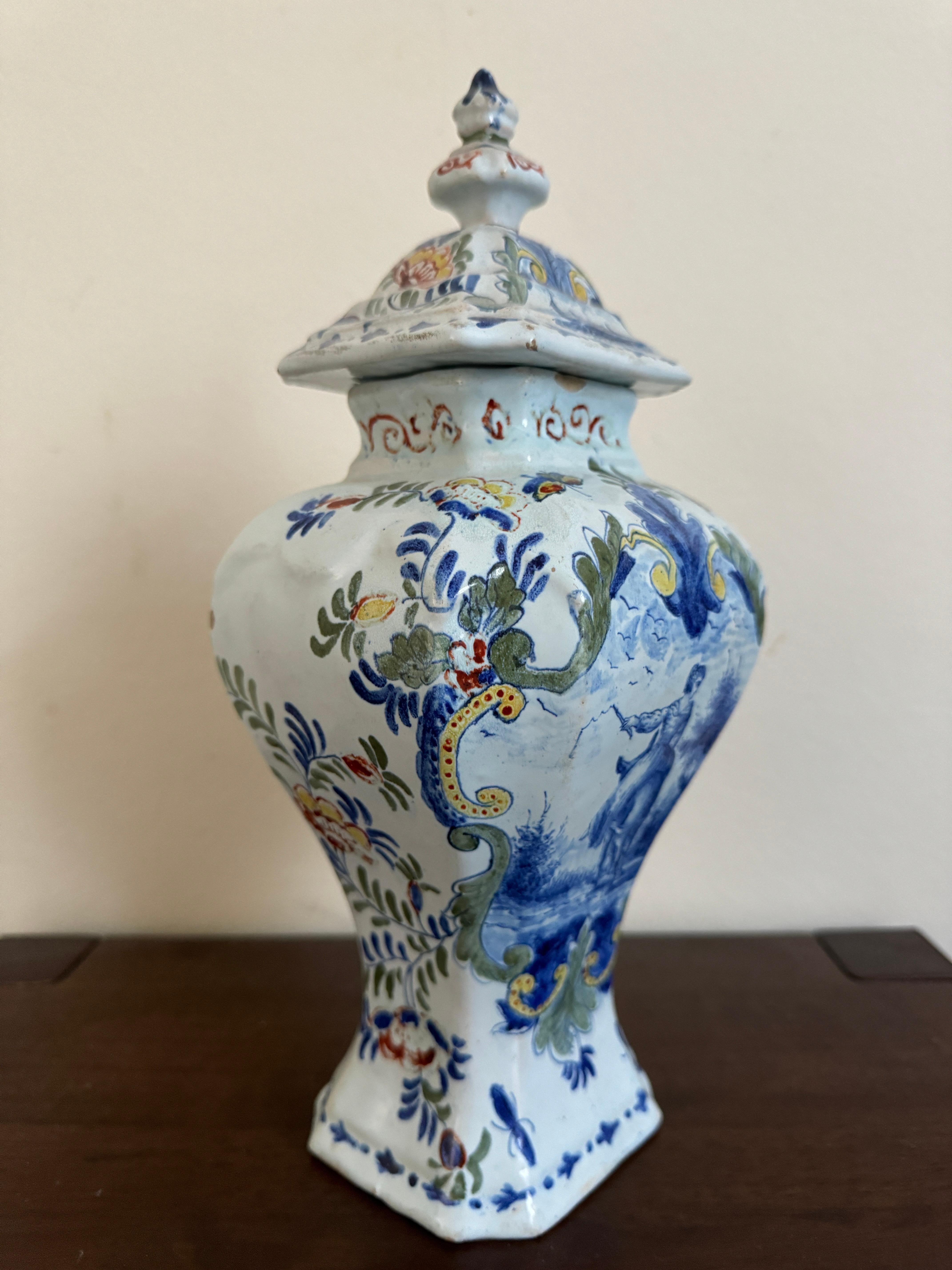 A good 18th Century Dutch Delft Baluster Vase,  the pale blue green ground having polychrome floral and fauna decoration framing a large central reserve featuring a cobalt courting scene. Marked to the bottom with the initials P.V.B in red.  

The