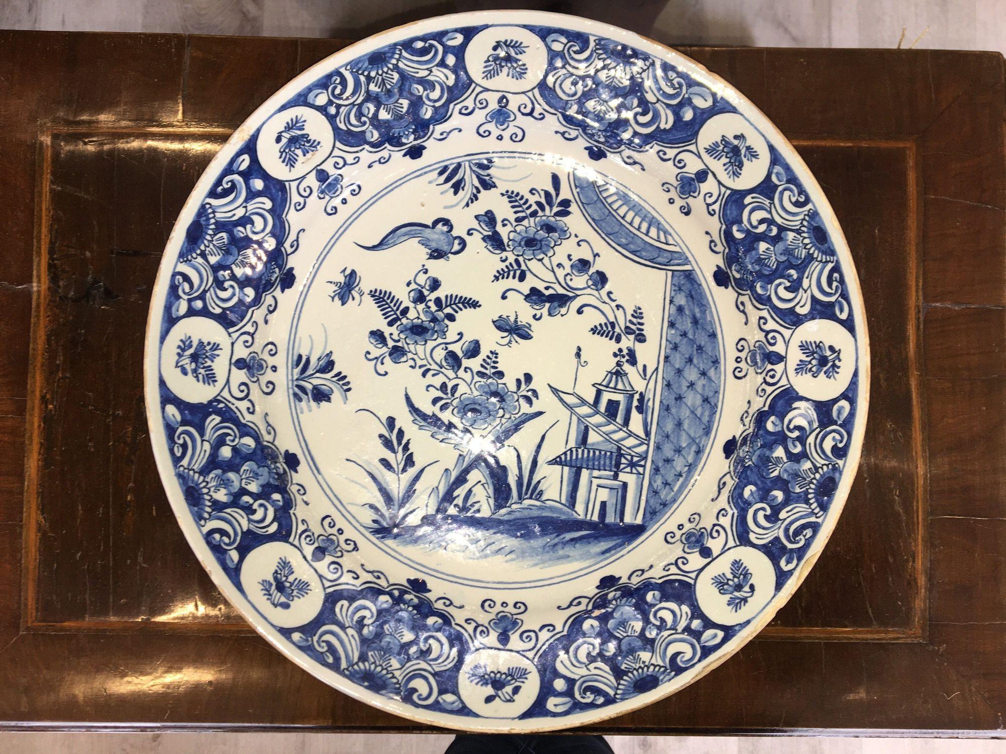 Dutch Delft Charger, 18th century, with chinoiserie bird, floral and building decoration, rim with scroll and paneled floral motifs, blue swirl mark on base, 14 1/8