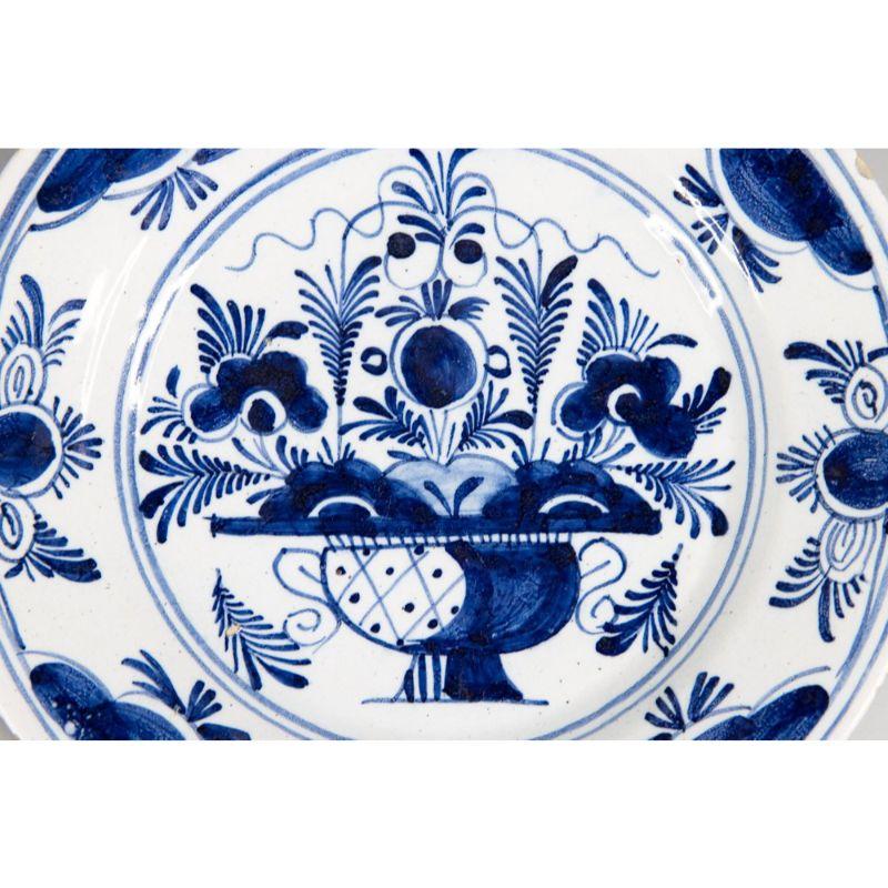 Ein wunderschöner antiker Blumenteller aus niederländischer Delfter Fayence aus dem 18. Jahrhundert. Dieser schöne Teller hat einen handgemalten Blumentopf in der Mitte mit einem dekorativen Rand in leuchtendem Kobaltblau und Weiß. Es würde an einer
