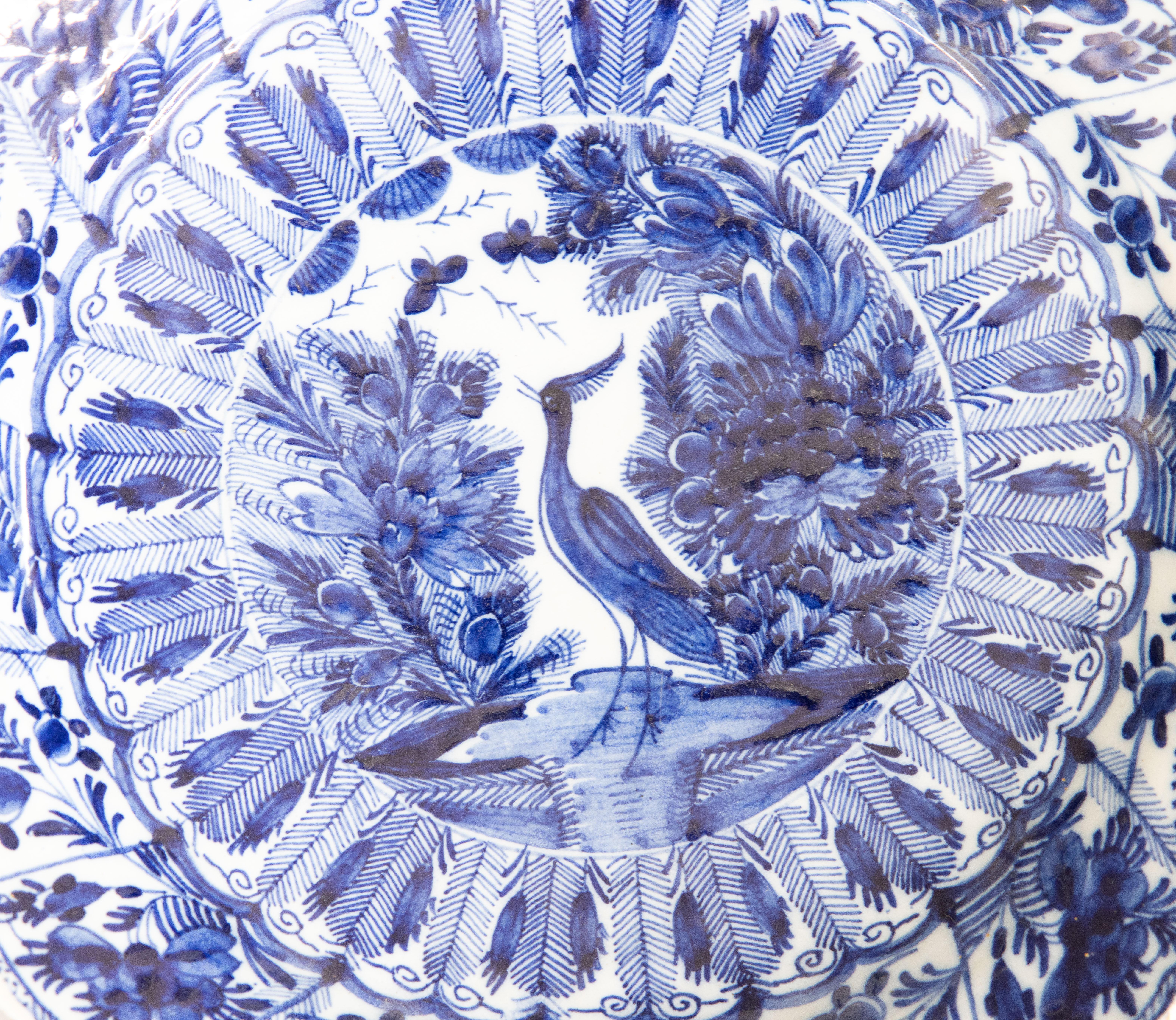 Magnífico cargador de pájaro pavo real de la fábrica De Klaauw (The Claw) de loza holandesa de Delft del siglo XVIII, hacia 1780. Firmado en el reverso. Este exquisito plato grande tiene una grulla pintada a mano, insectos, plumas, frutas y diseños