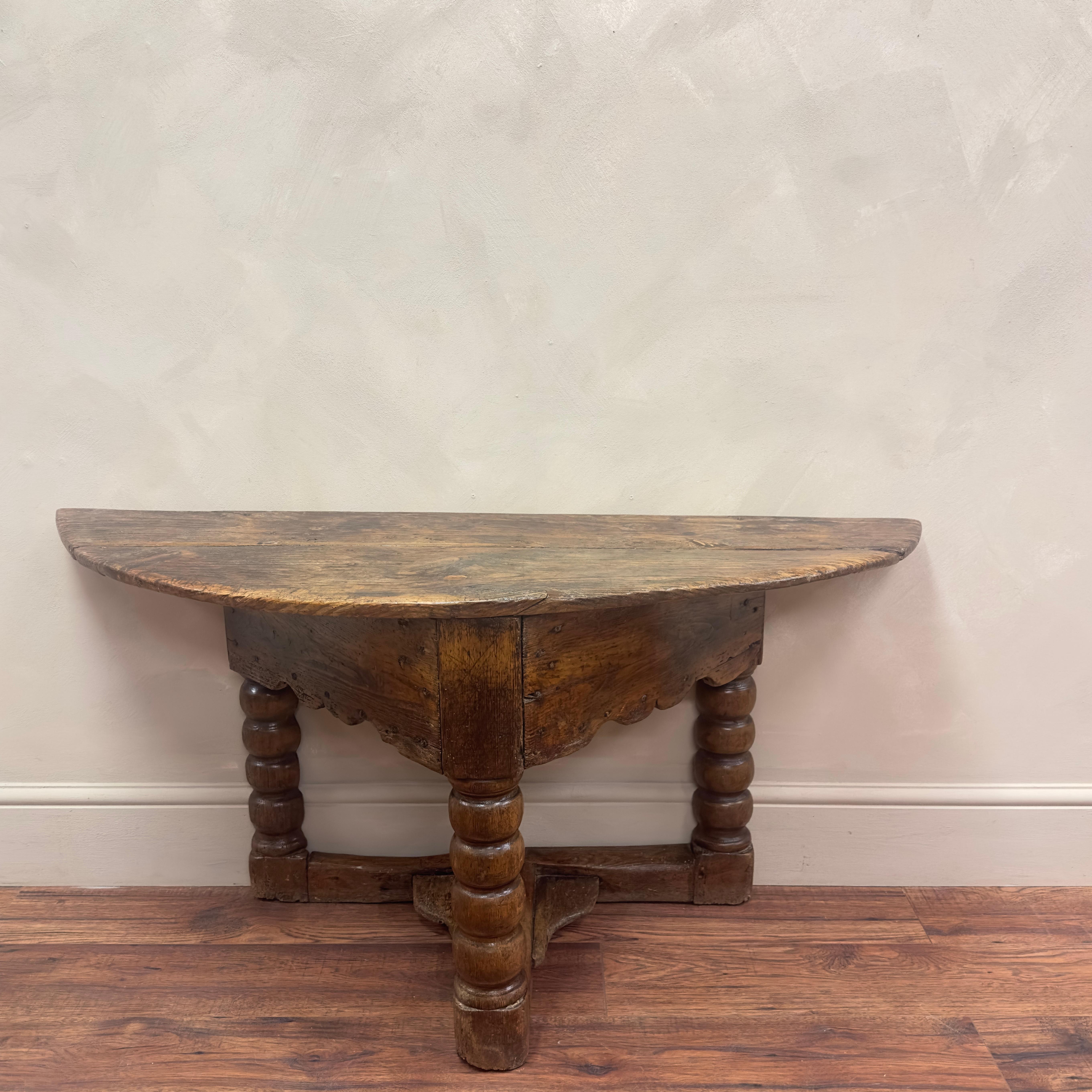 This wonderful demi lune console table was purchased privately and has been in the same house for many years.
Constructed from elm and oak, with the use of rosehead nails, the time worn wood has wonderful wear and colouration.
The shallow depth