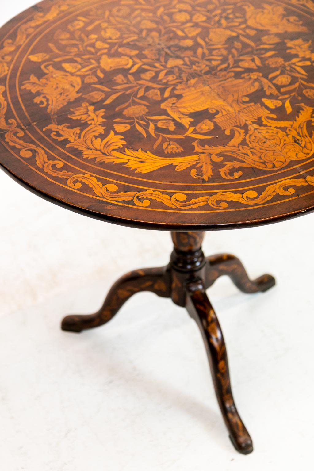 18th century Dutch floral marquetry tilt top tripod table is inlaid with avian, floral, and urn inlays with arabesque and lime border.