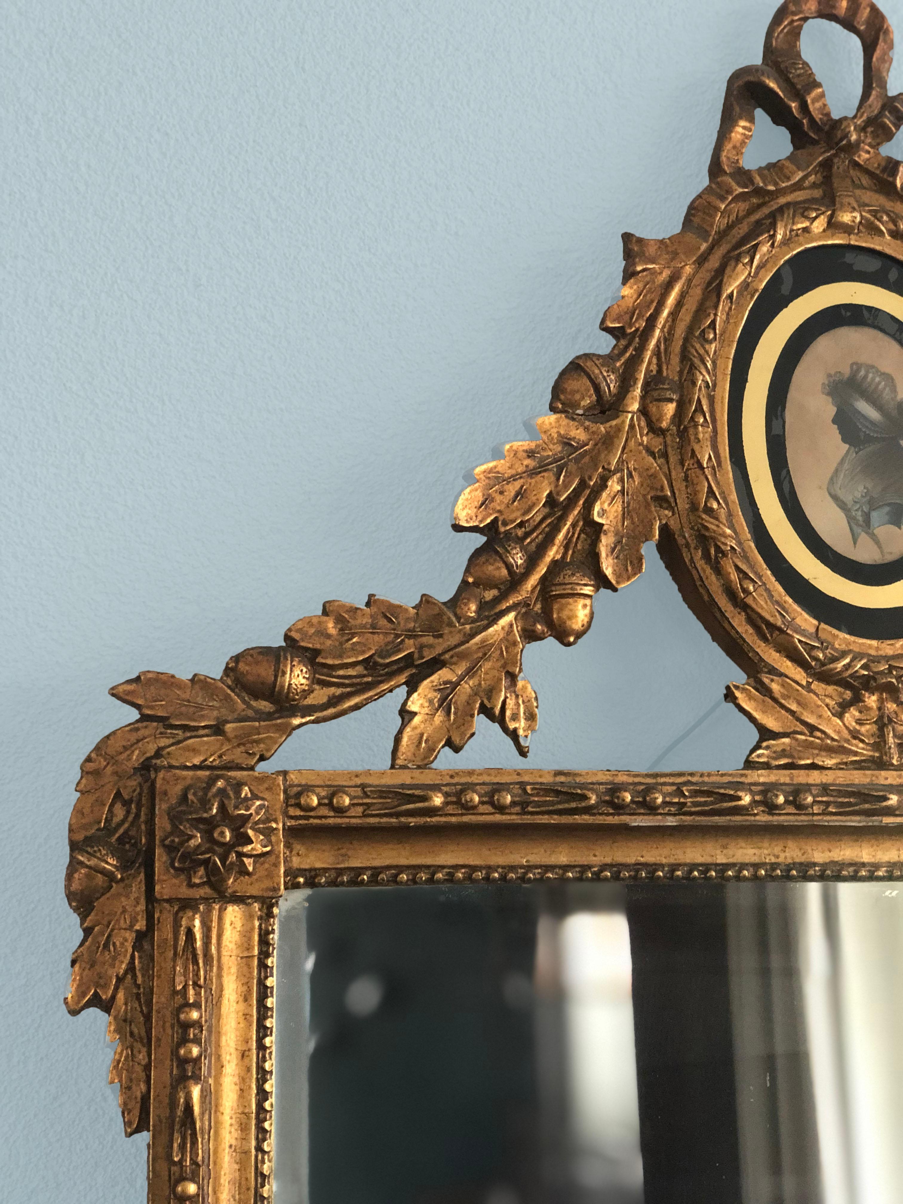 A Dutch 18th century rectangular giltwood Louis XVI mirror in very good condition. The mirror has a basswood frame surrounded by a pearl rim with decoration of bay leaves and berries. On the top it has a medallion in 'Verre églomisé' with a