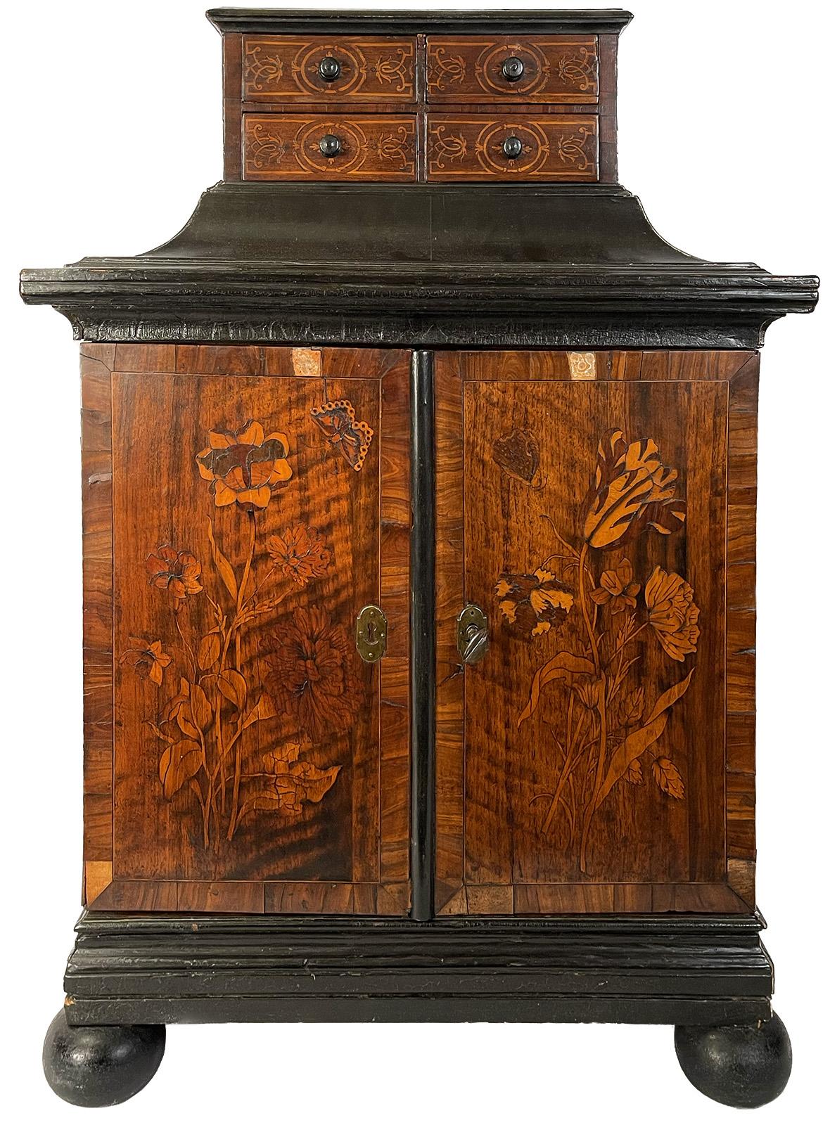 An 18th century Dutch jewelry or valuables cabinet, with four inlaid drawers on top and butterfly and floral marquetry inlaid doors opening to fifteen marquetry drawers.

Dimensions: 27.5