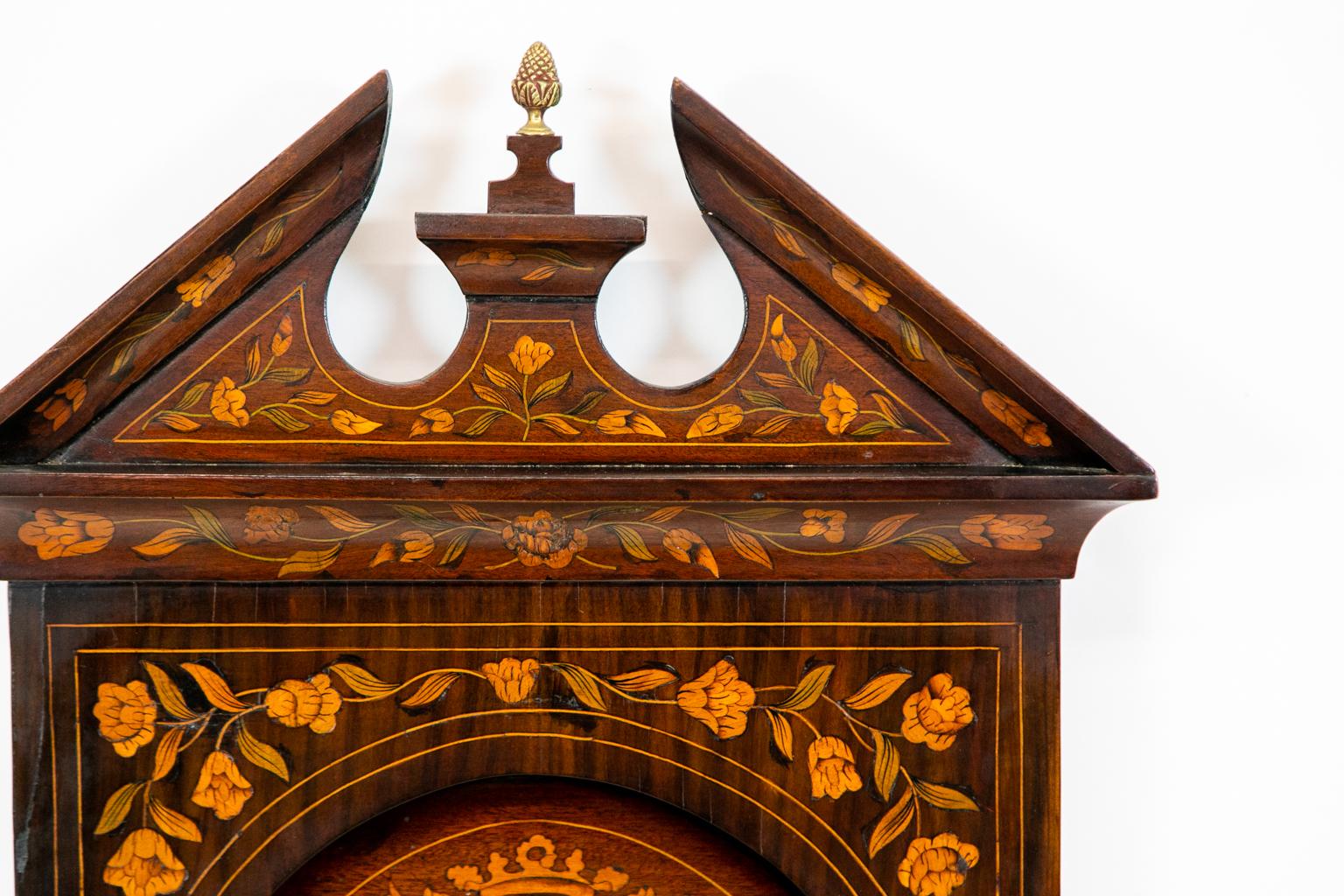 18th century Dutch Marquetry mirror, inlaid with flowers and vines with heraldic crests. It has a broken arch pediment with a brass pineapple finial.  The mirror is 4.75'' deep at the cornice,  34.25'' wide at the cornice, 29.25 '' wide at the