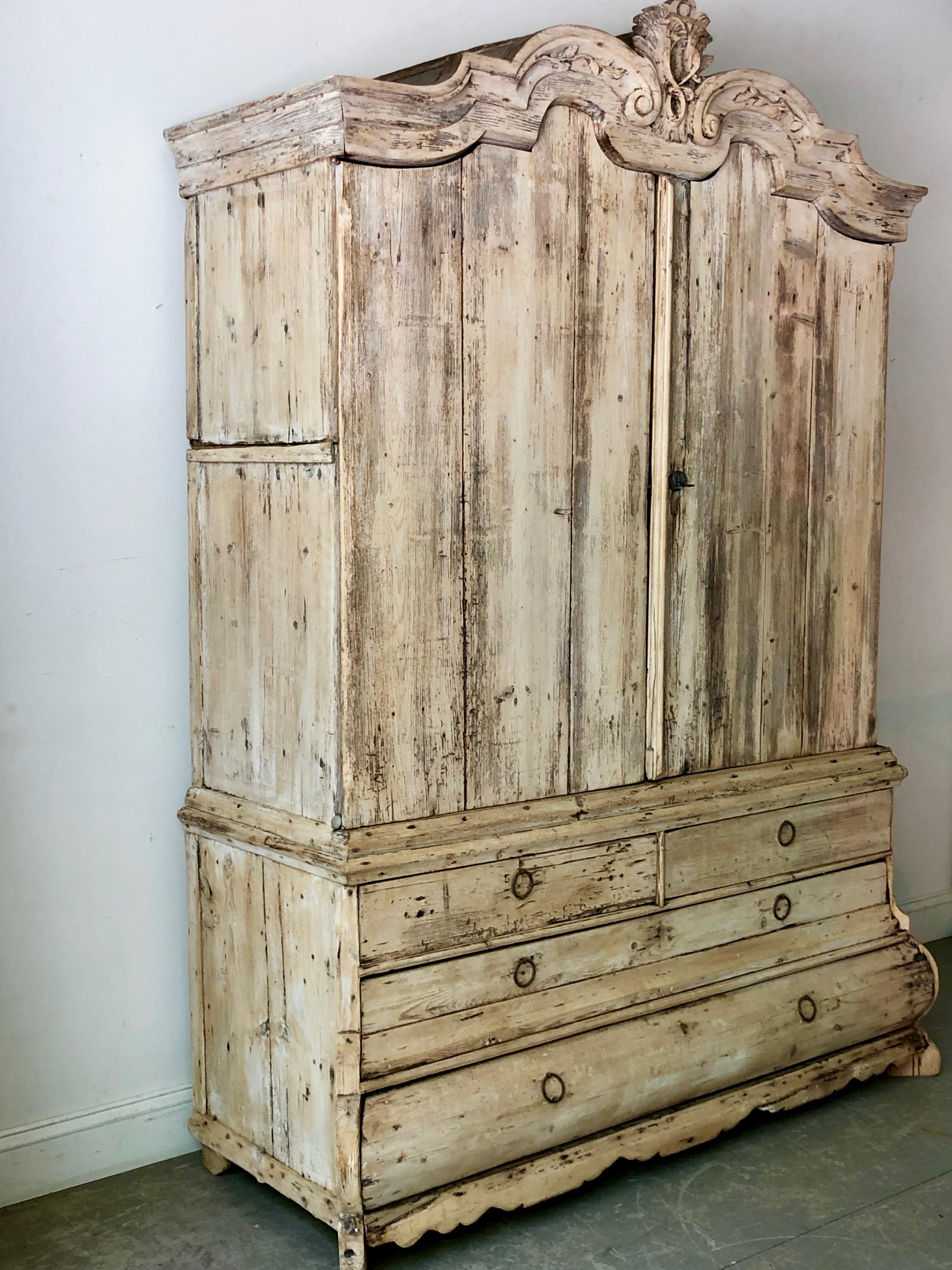 18th century Dutch beached oak two-piece cabinet with bonnet shaped pediment with delicate flower carvings,. The upper cabinet sits atop four bombé drawers with calloped skirt and carved feet.