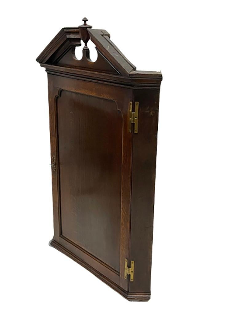 18th Century Dutch oak hanging corner cabinet.

An antique Dutch oak corner cabinet, hanging model with an ornament of a vase. The cabinet has an interior of 3 shelves and the door with a panel is hanging from copper fittings (hinges). The lock is