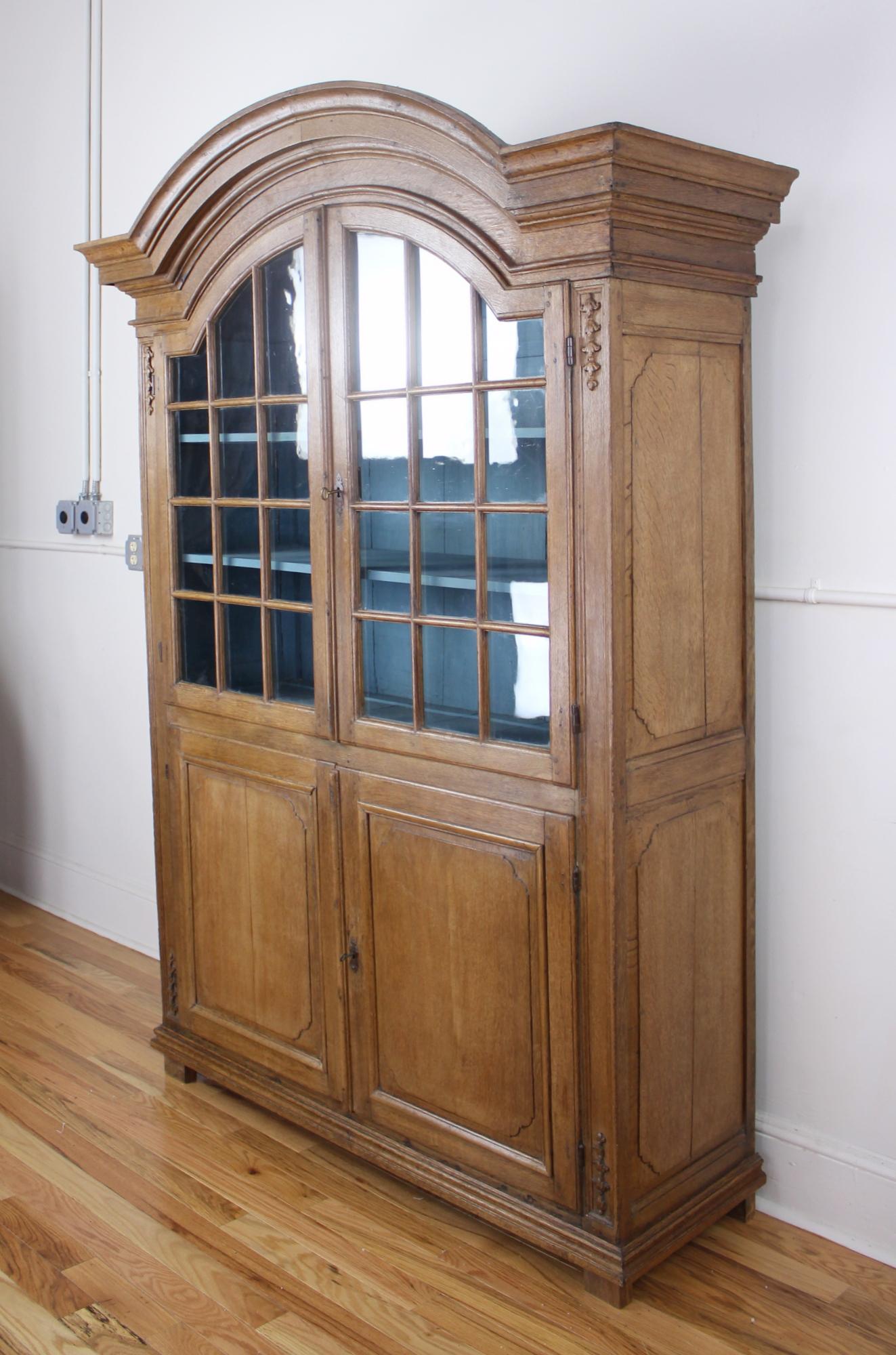 A spectacular early Dutch vitrine in polished oak. We believe this piece to be from delft, originally configured in the upper cabinet to display blue and white traditional delft porcelain. Now reconstructed for modern use. Newly painted blue
