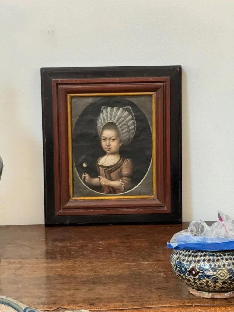 Ritratto olandese di una giovane ragazza olio su tela, 1750 circa, dipinto in ovale, la ragazza con una cuffietta di pizzo e con in mano un bocciolo di rosa bianca, montato in una cornice in legno ebanizzato e dipinto.  14,5 x 12,75 la cornice