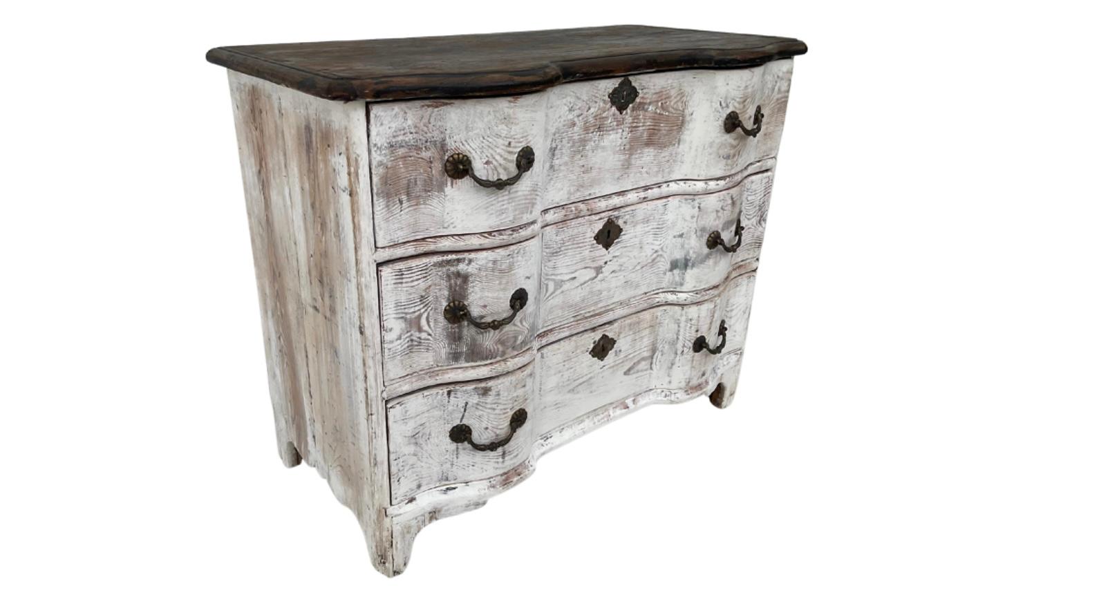 This is a beautiful Dutch Rococo commode, circa 1760 in white wash paint with original bronze hardware. The commode has a double serpentine front, shaped top, and scalloped apron. There are three spacious drawers with plenty of storage options. Faux