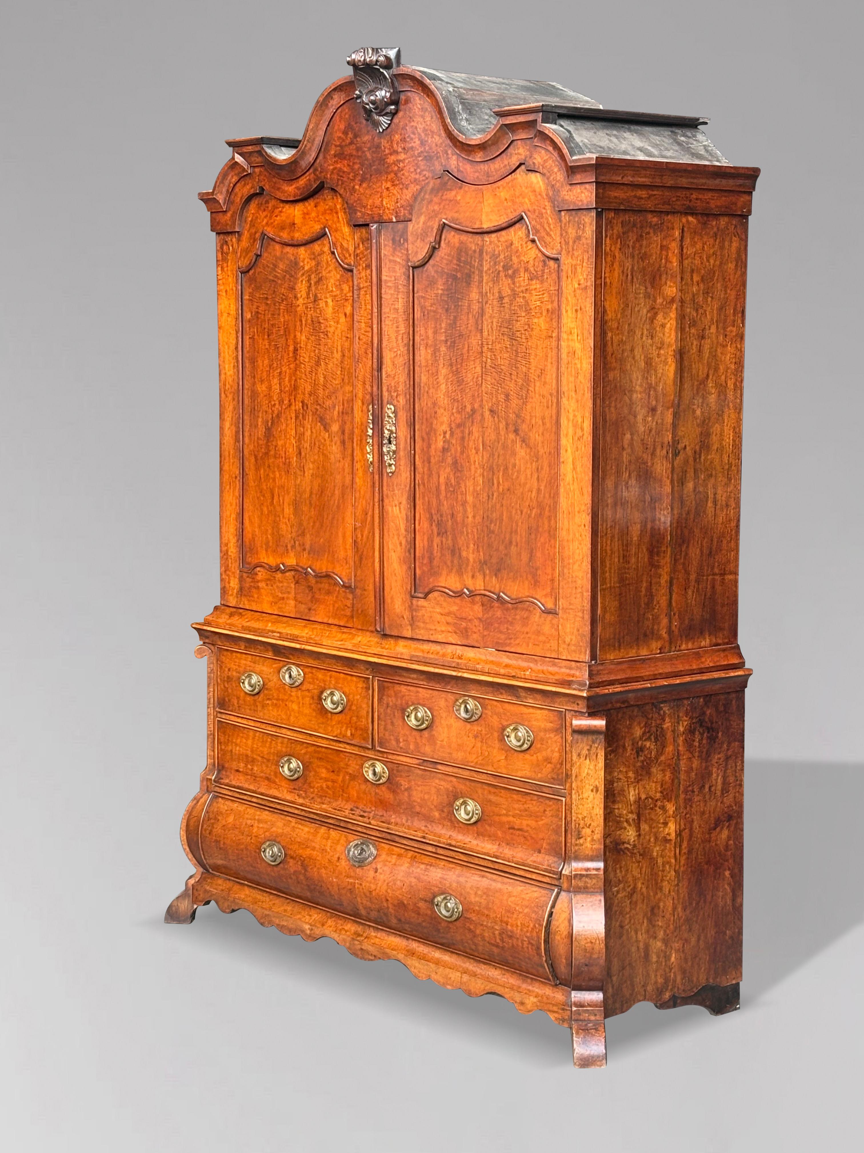 A very fine mid 18th century three part Dutch rococo walnut cabinet on a bombé chest. A decorative carved arched pediment with carved shell crest and a finely moulded cornice above two wavy top shaped panelled doors, opening to storage shelves with