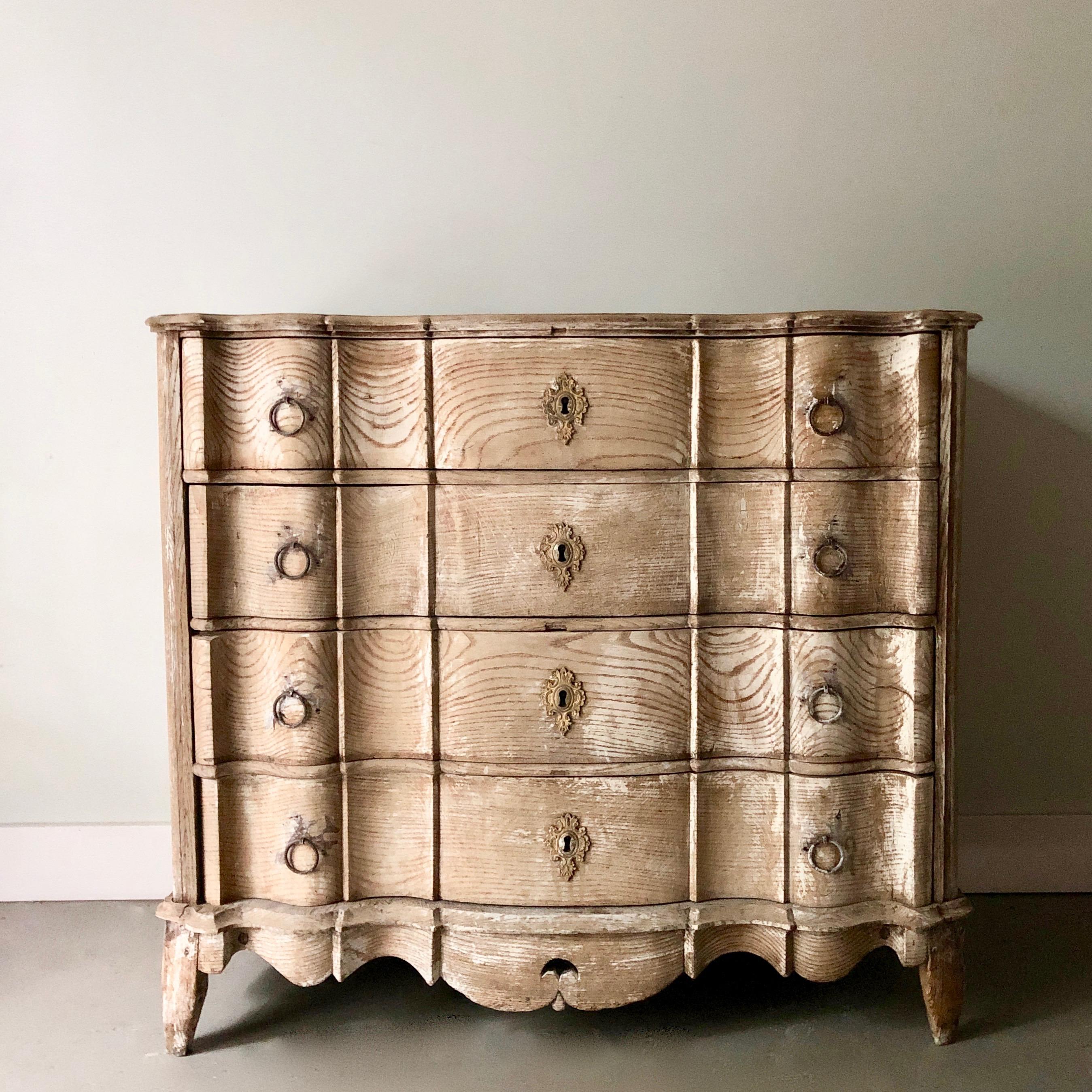 18th century four drawers Dutch chest in richly carved bleached oak with curvaceous serpentine drawer fronts, shaped top, handsome original large iron handles on the side panels and beautifully carved apron and feet.
Note: the one old darker spot