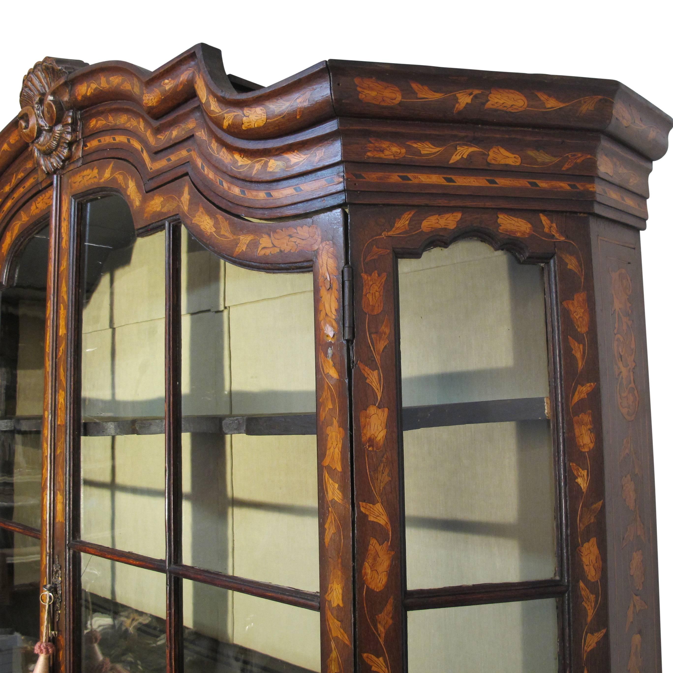 A beautiful example of an early 18th century Dutch cabinet. Walnut with fruitwood inlay marquetry design of leaves, flowers and urns. Having its original shelves, original hardware, and most of the original glass. Recently re-lined interior in silk