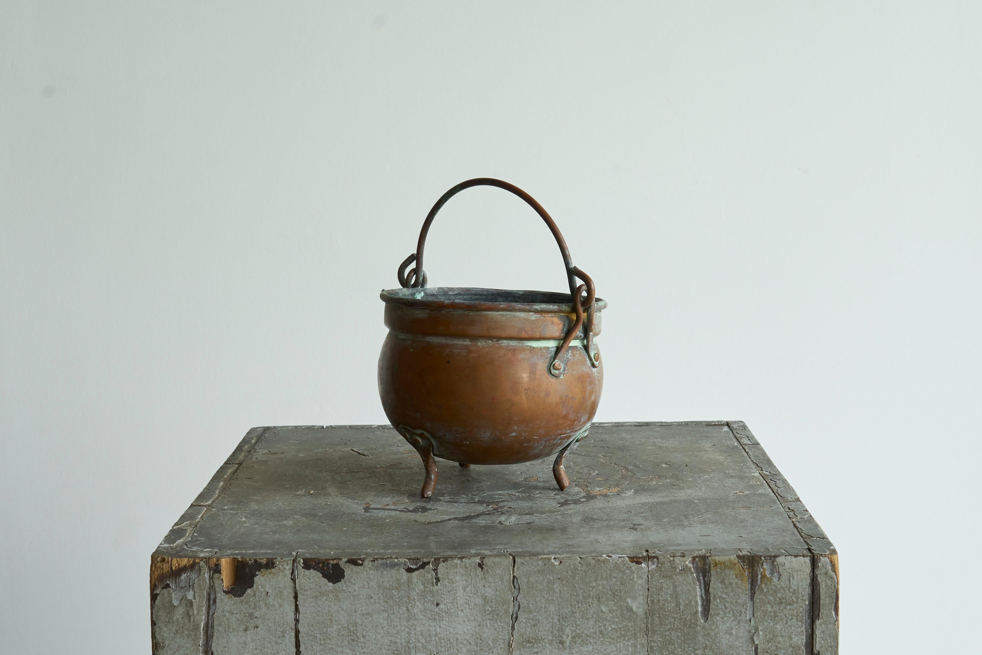 18th Century Eared Pot in Patinated Copper

An 18th century eared tripod cooking pot in patinated copper.

Round-bodied cooking pot in hand-formed copper with fixed handle and tripod feet. The surface shows a deep patina with areas of verdigris at