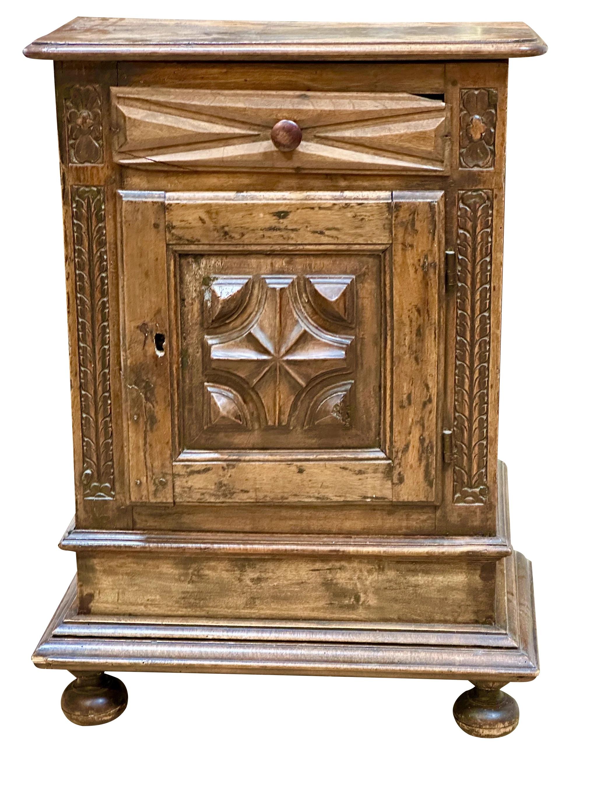 Early Tuscan, Italian walnut cabinet, largely 18th Century with restorations, having a drawer over a deeply carved hinged door over ball feet; 26 inches wide; 14 inches deep; 37 inches high
