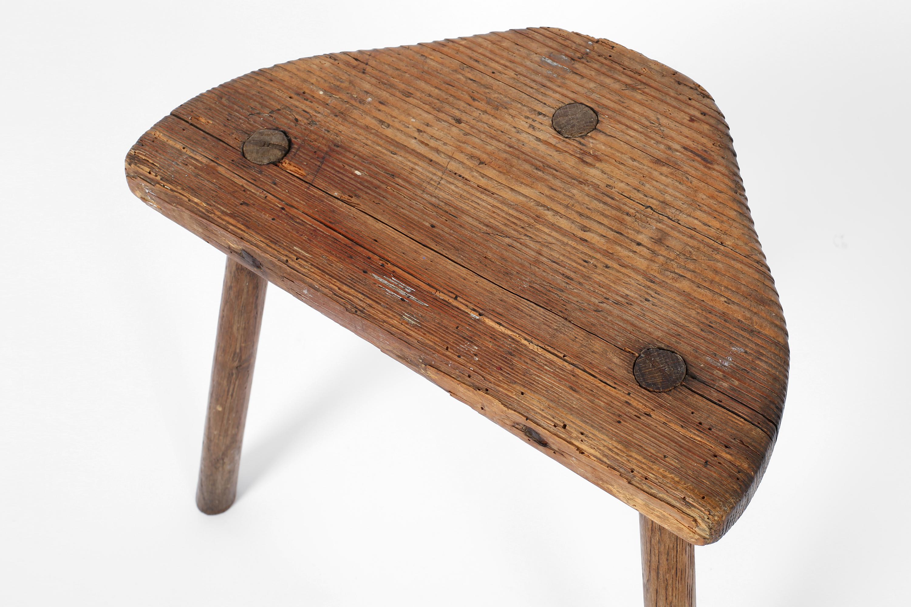 A George II era tripod milking stool in patinated elm. England c. 1750.