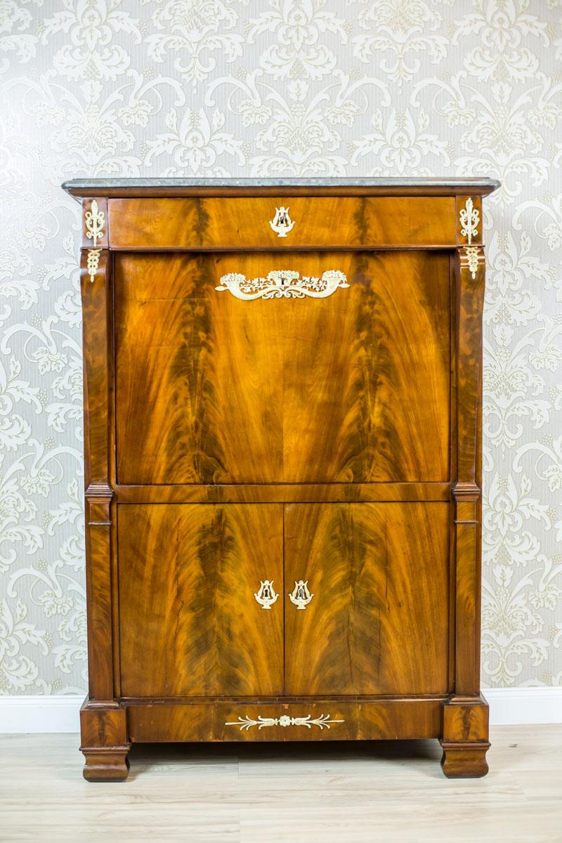 We present you an antique piece of furniture covered with mahogany veneer with beautiful grain. It is topped with a green marble board.
The whole is dated the turn of the 18th and the 19th centuries.
This secretary is composed of a double-leaf