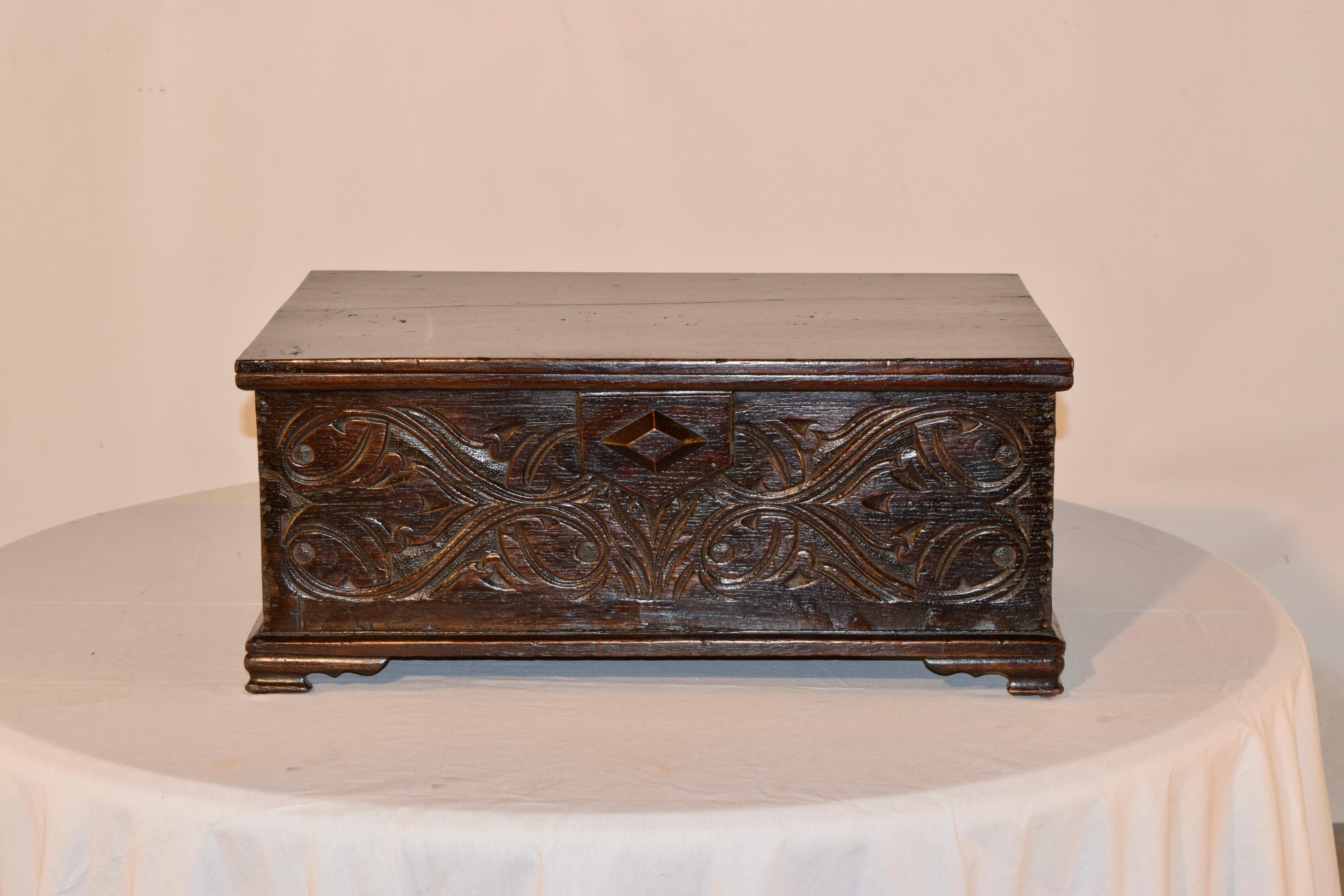 Mid-18th-century bible box from England, made from oak. The top is made from two boards, and rests on the box, which is hand carved decorated on three sides. The box has pegged construction and has pie crust edges on the sides of the front panel.