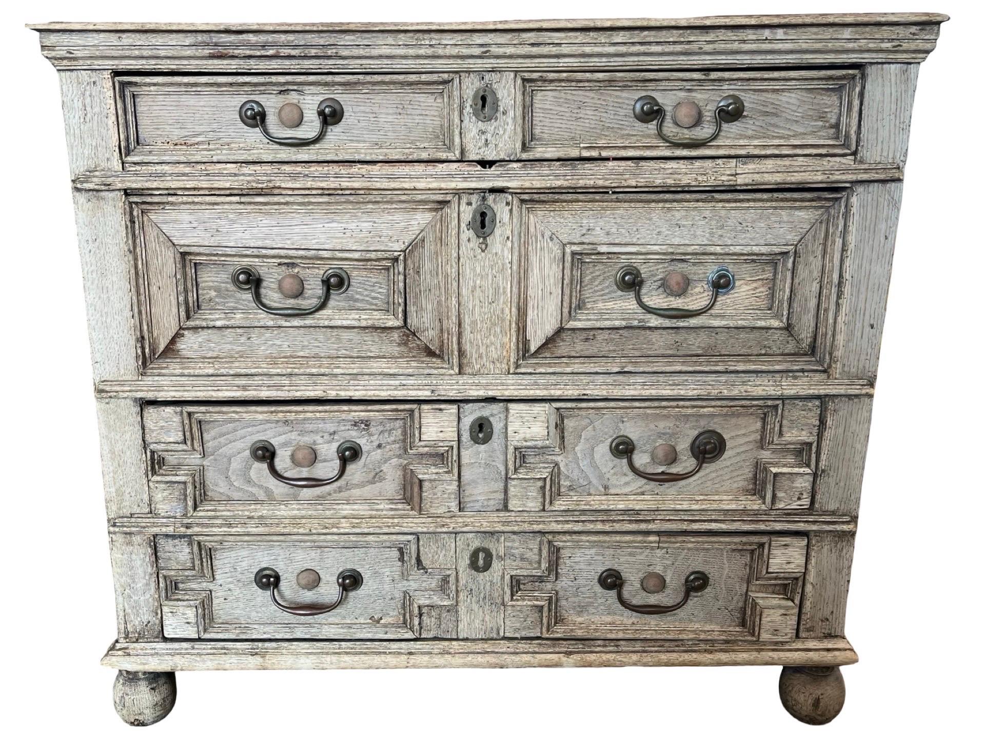 Jacobean chest of drawers hand-made in the United Kingdom in the early 1700s using oak. The chest features four inset drawers of different depths and decorated with different patterns of moldings on the drawer fonts. As typical with the style the