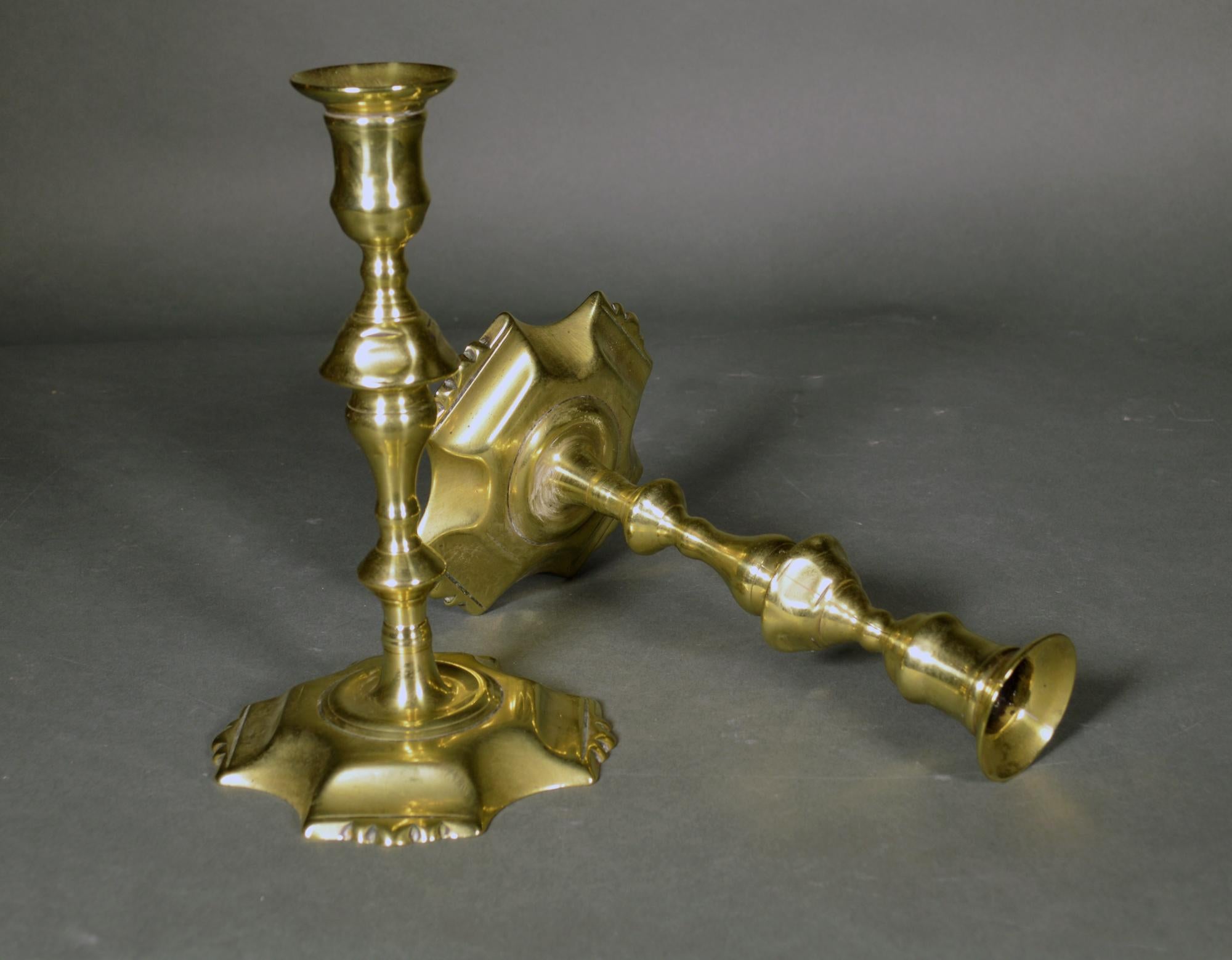 English brass petal-base candlesticks,
A pair,
circa 1760-80

The English brass candlesticks have a petal base with four sides and a concave indented design between the fluted petals. The central column with a series of projects including the