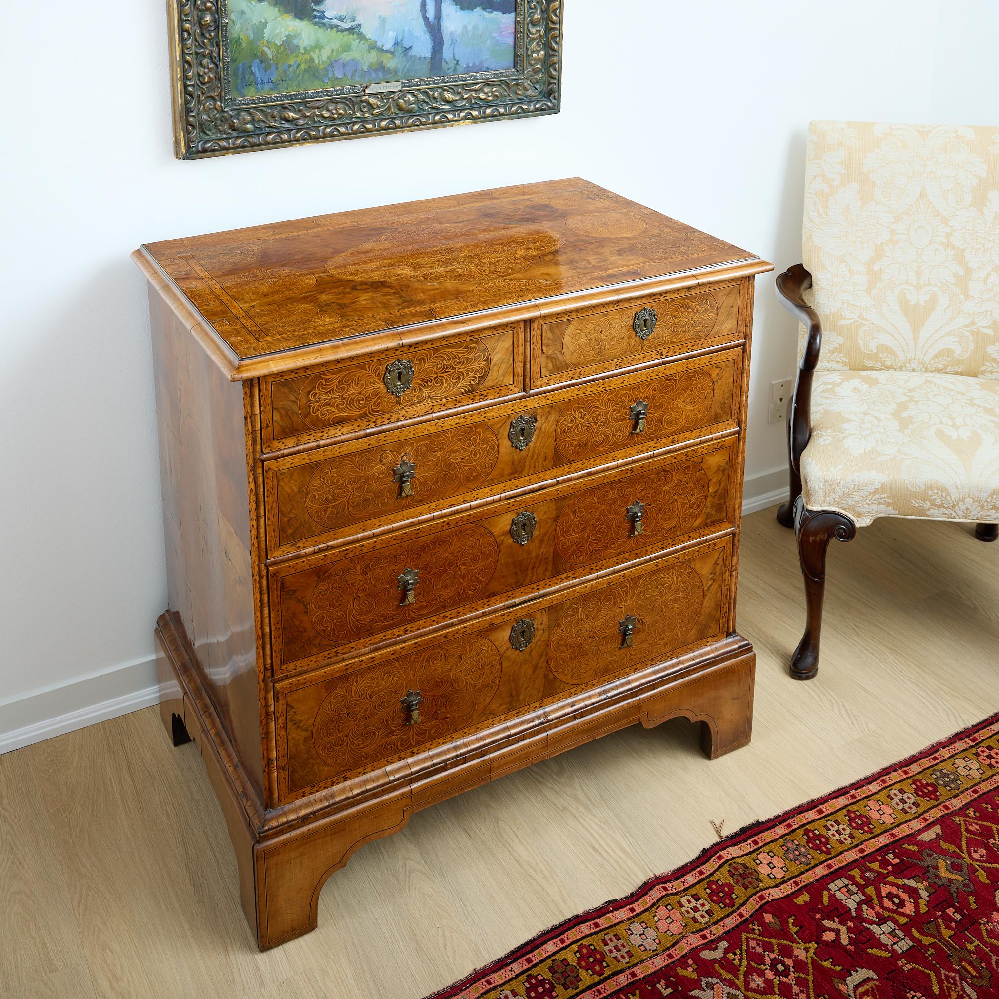 A spectacular 18th century, English, five drawer chest with burled walnut and inlaid fruitwood marquetry throughout. Each drawer has a brass escutcheon and drop pulls, all original. The sides have patchwork veneer and central scrolling marquetry