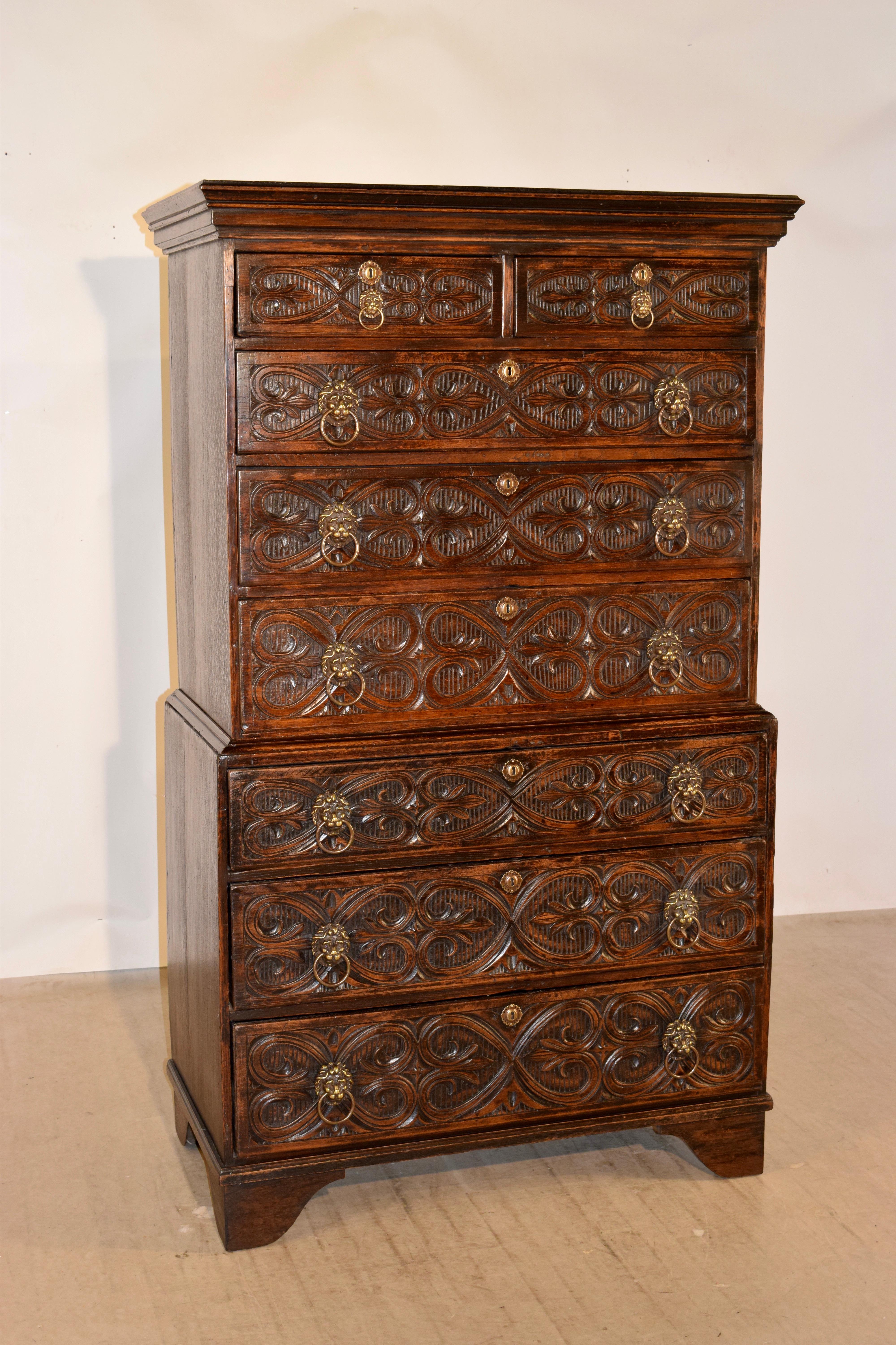 18th century English oak chest on chest with lovely crown molding around the top, following down to a two-piece case which has two drawers over six drawers. The drawers fronts are all hand carved decorated and have the most wonderfully hand cast