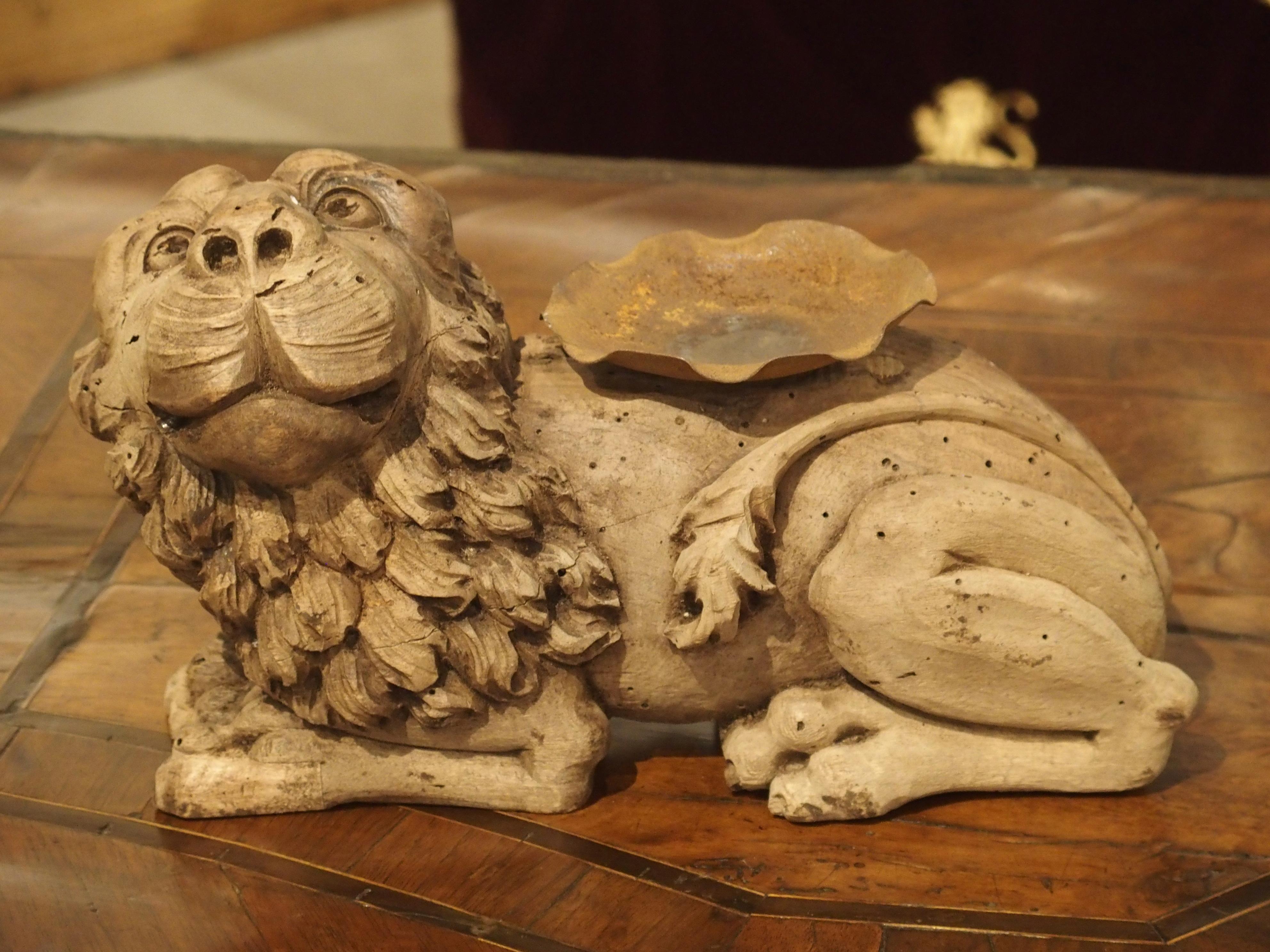 Originally part of an architectural fragment or a decorative piece of a large furniture, this carved antique lion has been repurposed into a candleholder with an iron bobeche.

The hand carved lion faces to the left and is looking up with an