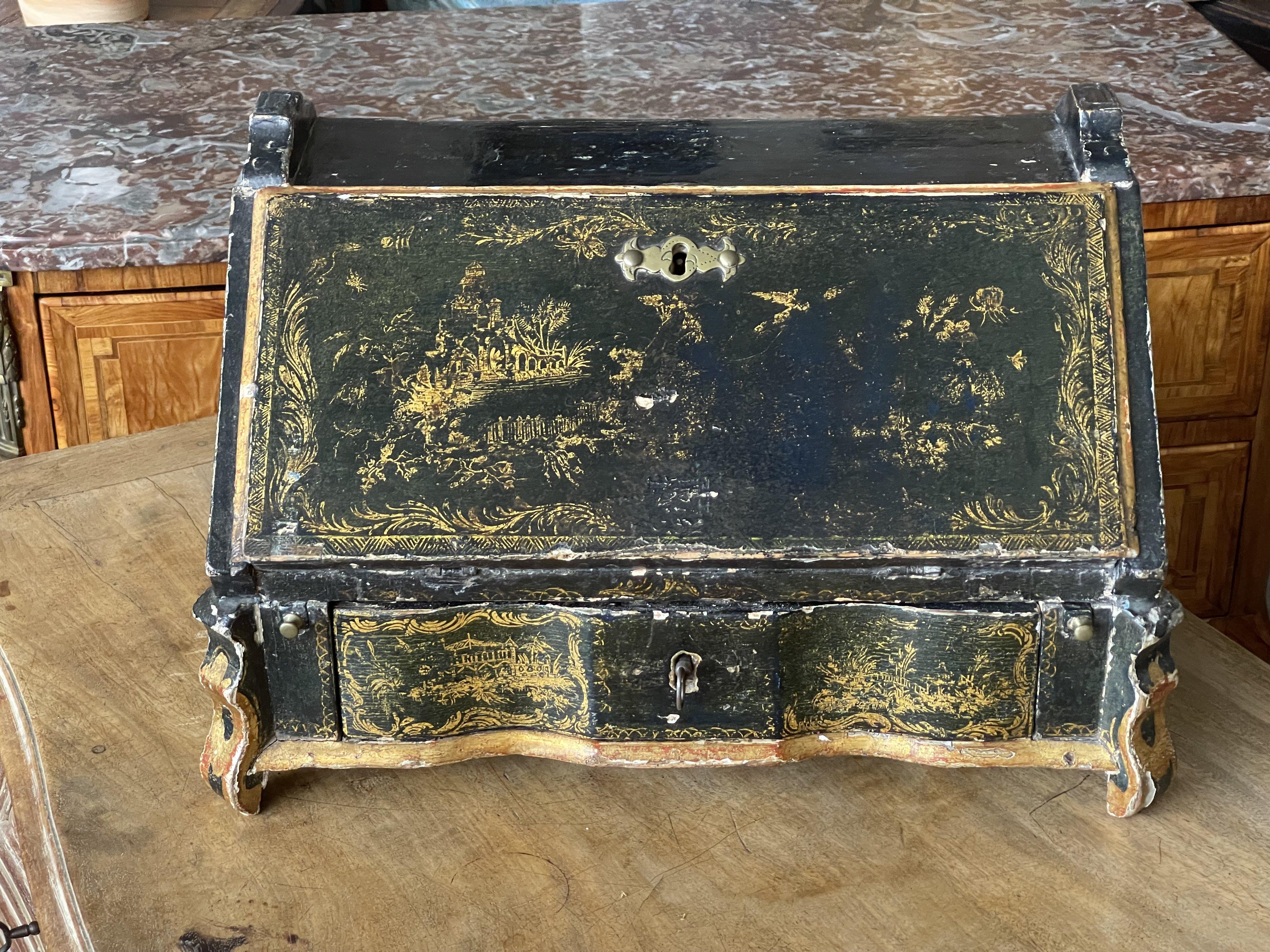 18th Century English Chinoiserie table desk, having a drop-down front revealing five interior drawers and two cubby holes, over a larger serpentine locking front drawer (with key) flanked by two pulls supported by curved feet, the piece lacquered