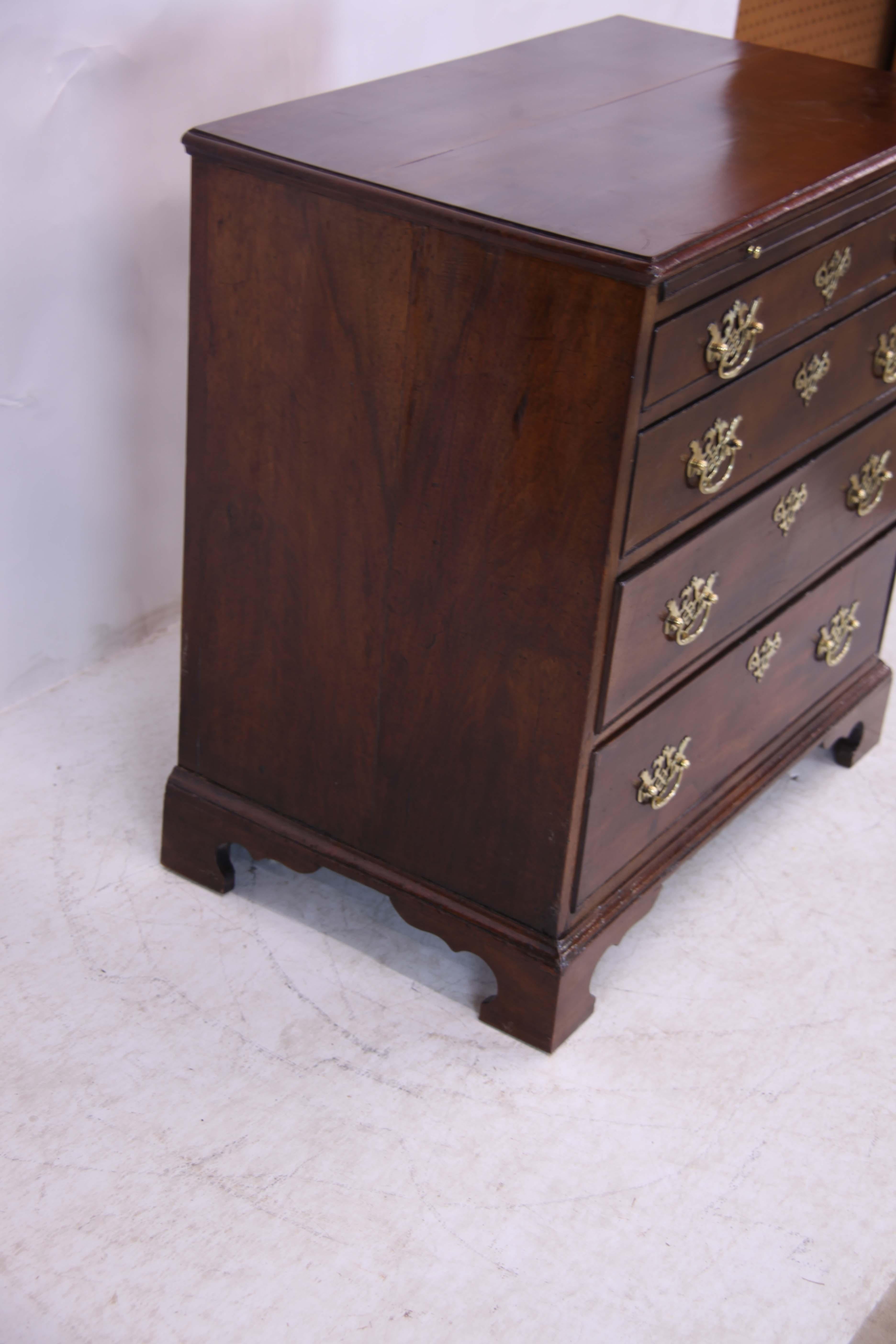 18th century English Chippendale bachelor's chest, having four cock beaded and graduated drawers with reticulated fretwork pulls below pull out brushing slide, on bracket feet.