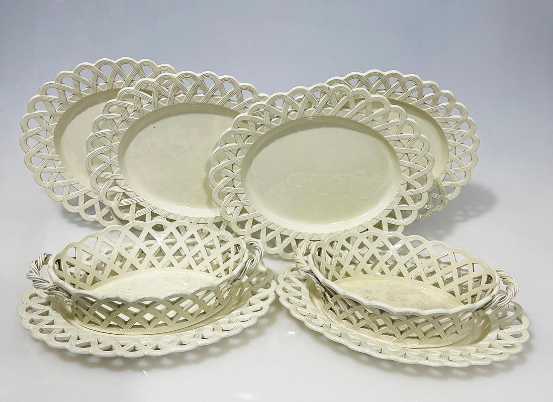 18th century English creamware baskets and plates

A set of 2 oval open woven baskets on an oval dish with open basket weave pattern rims and handles of a thin twisted pattern, decorated with flowers and leaves. English, ca. 1780. Four oval dishes