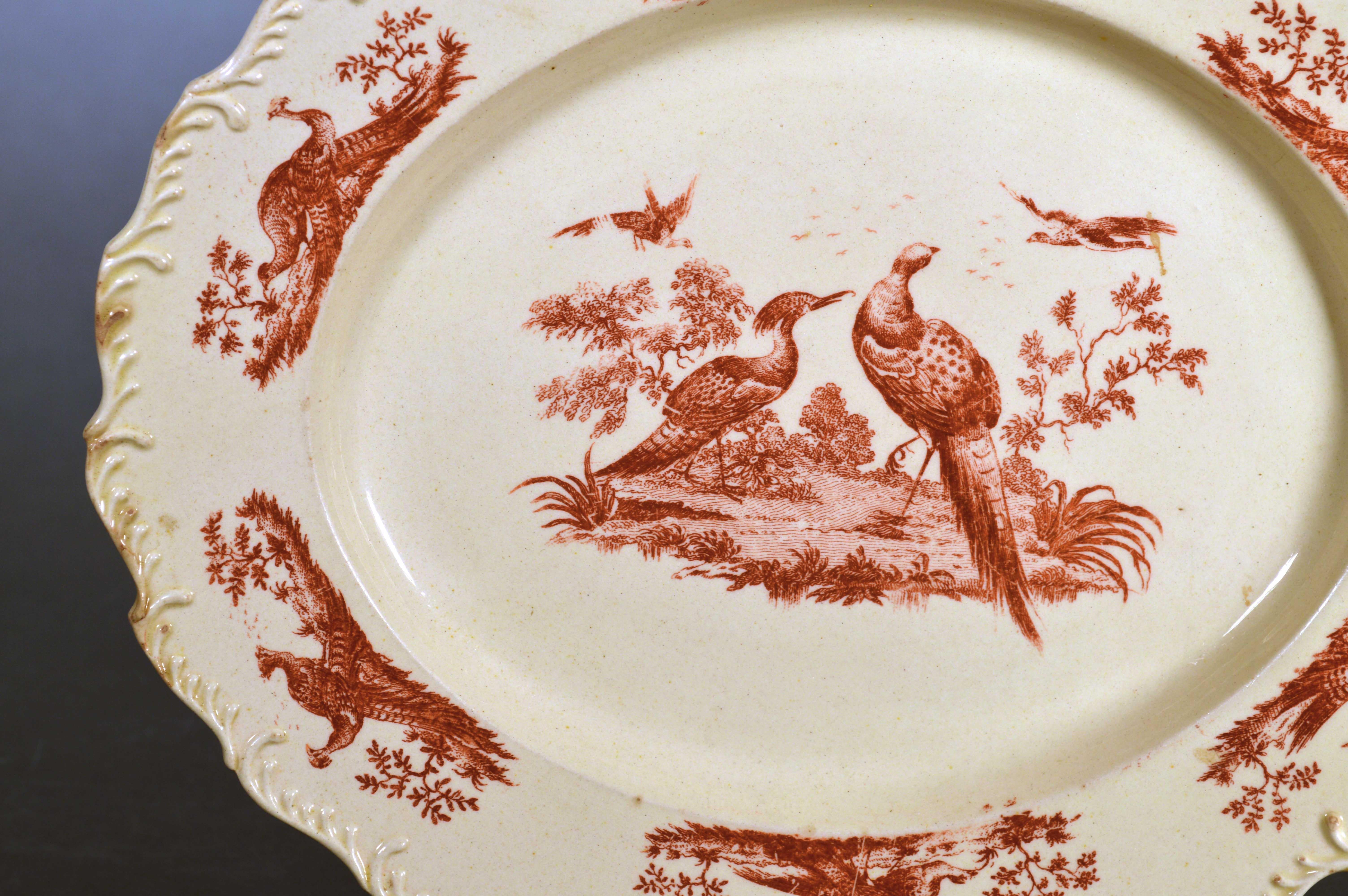 18th century English creamware dish with game bird decoration and feathered edge,
Josiah Wedgwood,
circa 1765,

The deep cream-colored oval creamware dish is decorated with printed exotic birds in carmine red created by Sadler & Green of Liverpool.