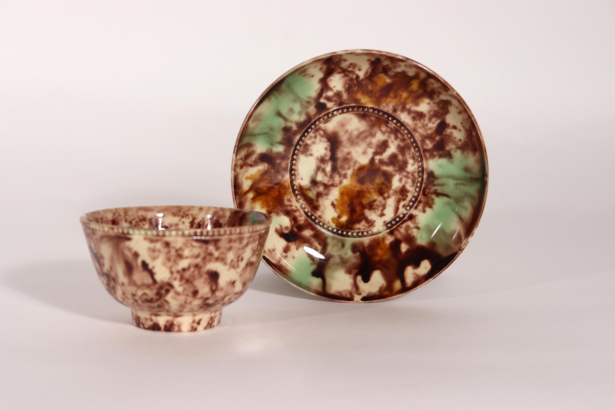 English Creamware Whieldon-type Tortoiseshell Tea Bowl & Saucer,

The 18th-century creamware tea bowl and saucer are decorated in tortoise-shell and green glazes.  The exterior of the bowl has a band of molded pearls as does the saucer around the
