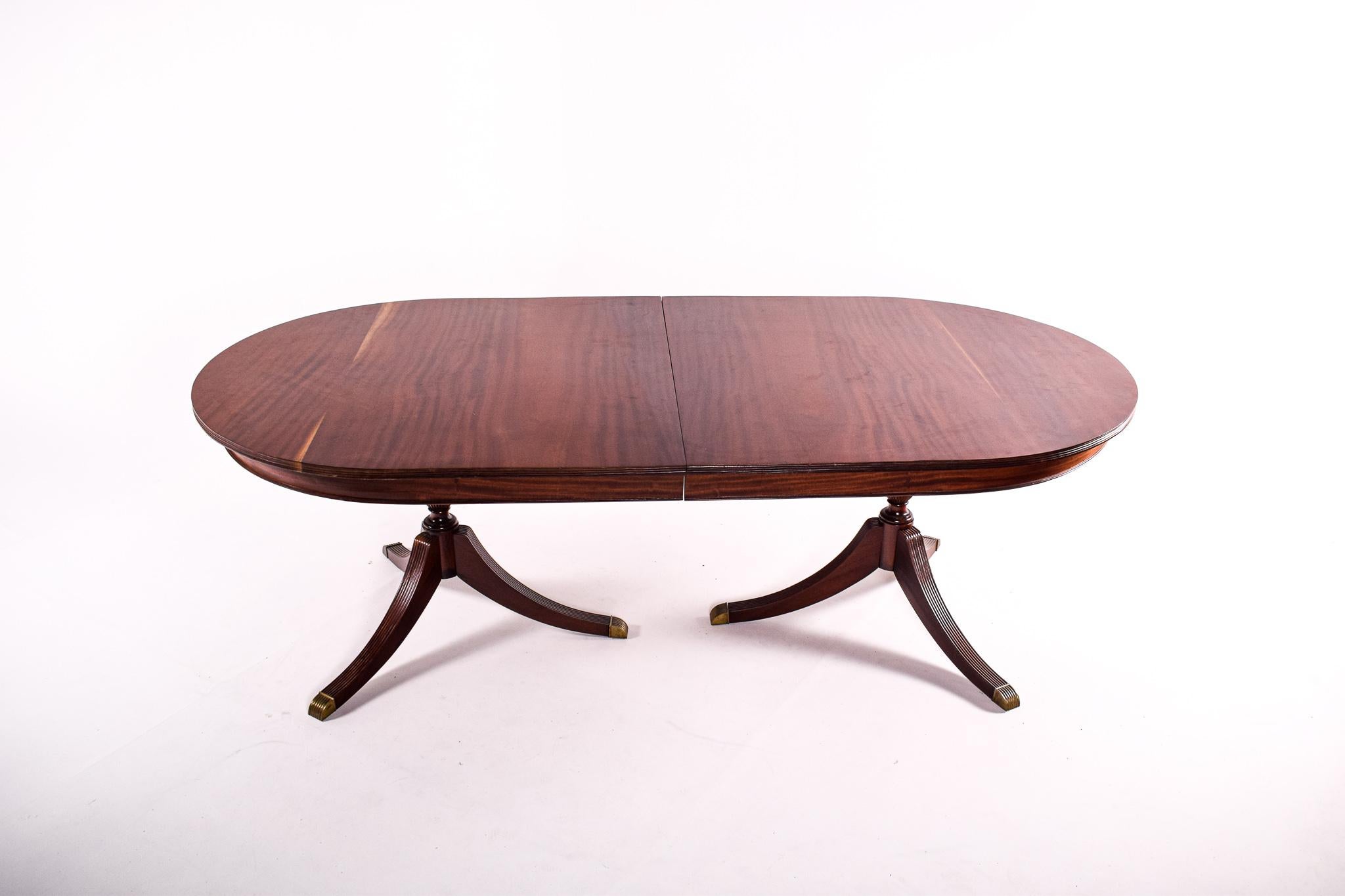  This stately dining table is a modern homage to the classic design sensibilities of 18th-century England. Showcasing the elegance and grandeur of that era, the table features a generous oval mahogany top with a rich patina that speaks to its age