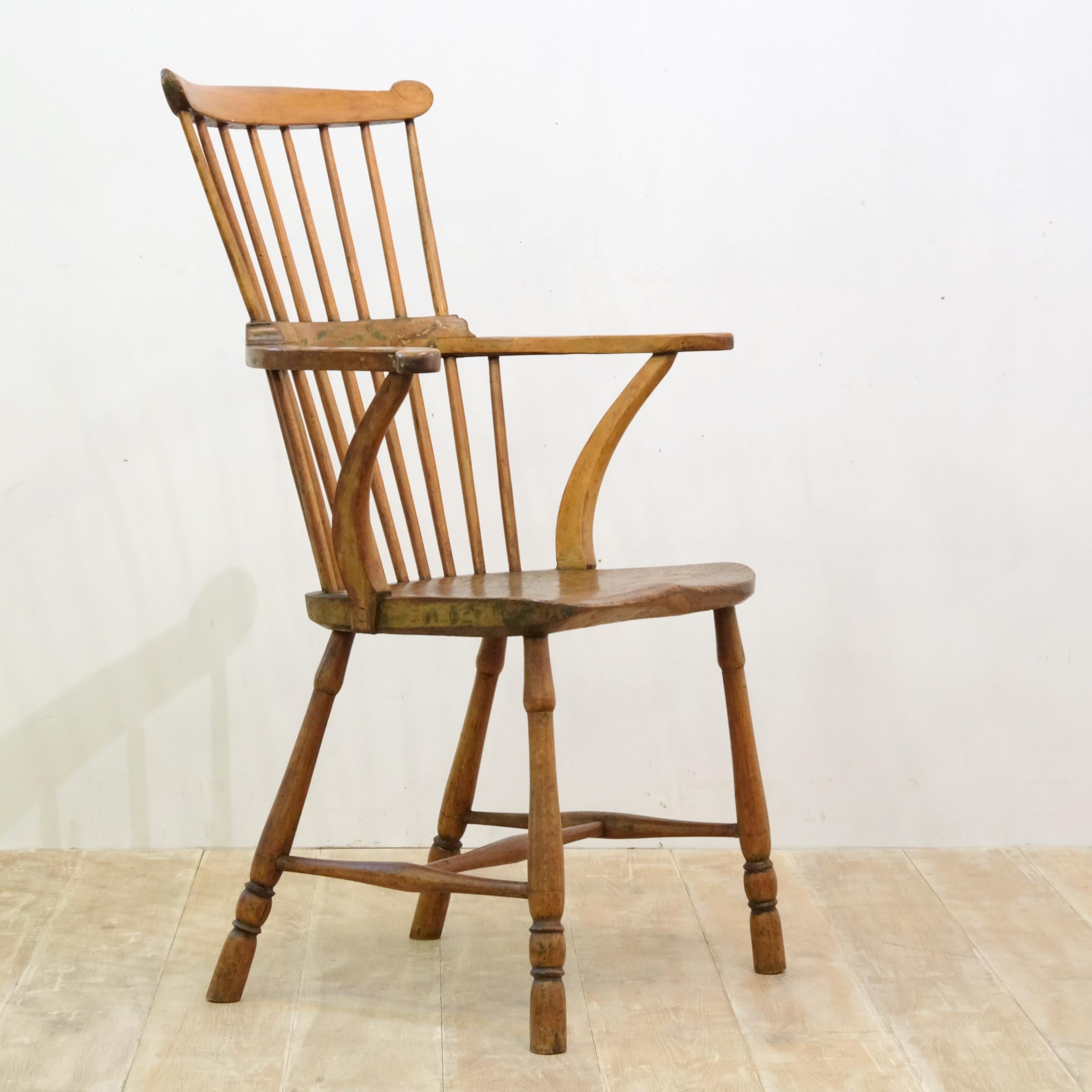 A rather wonderful George III provincially made comb back Windsor armchair. This country chair is perfectly formed and incredibly appealing. It exhibits plenty of its original green paint and the roughly hand-hewn elm seat has a sumptuous color and