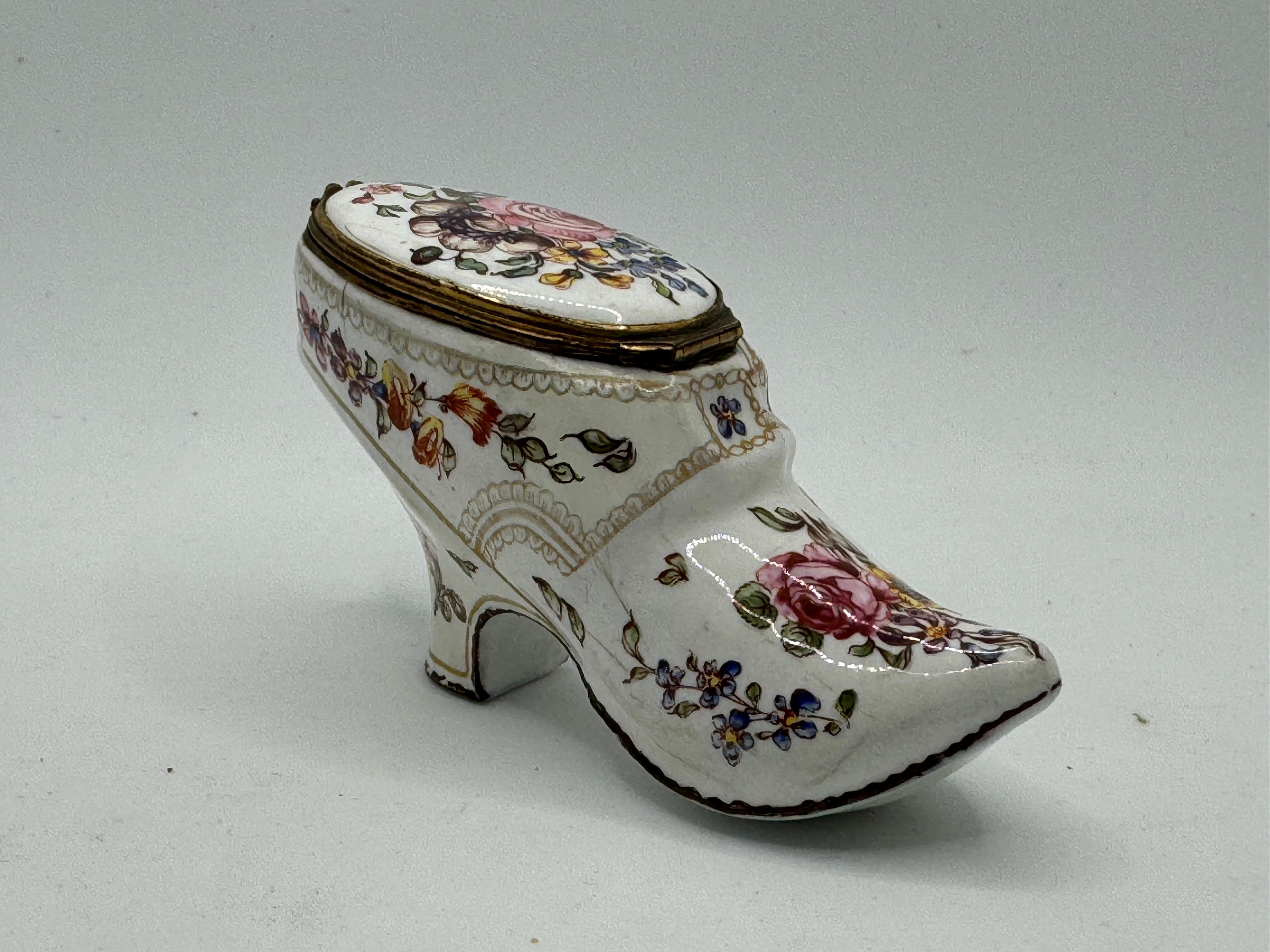 An English Enamel Shoe Shaped Bonbonniere, circa 1765
with an oval lid, painted with flowers and realistic details including a buckle. 4