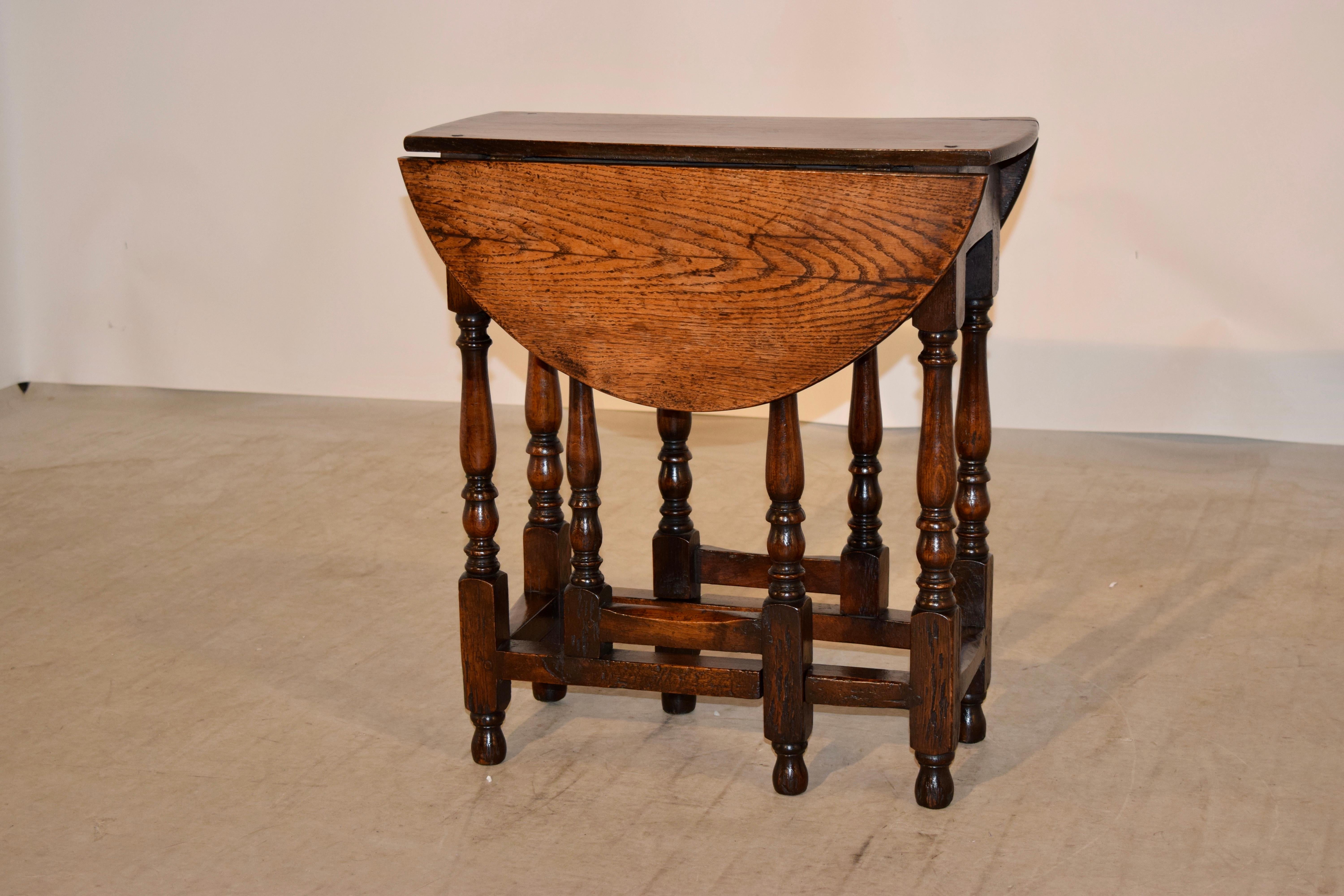 18th century English gate leg table made from oak. The top is pegged and follows down to a simple apron. It is supported on hand turned legs and gates, which are joined by simple stretchers. The top has shrinkage and staining from age and use and