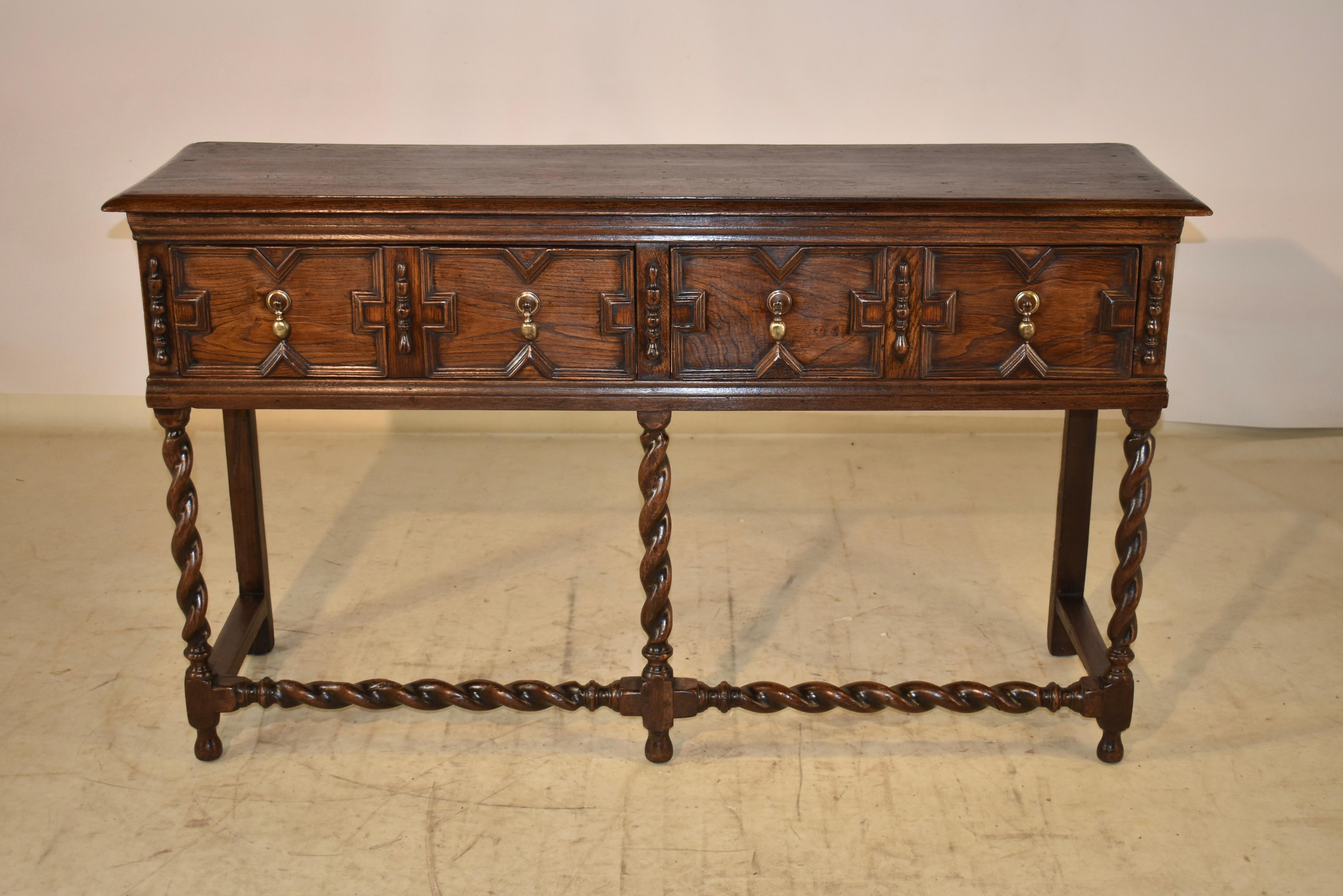 18th century oak sideboard from England with a beveled edge around the top, following down to paneled sides. There are two drawers in the front, both with raised panels and geometric moldings, flanked by applied turnings for added design flare. The